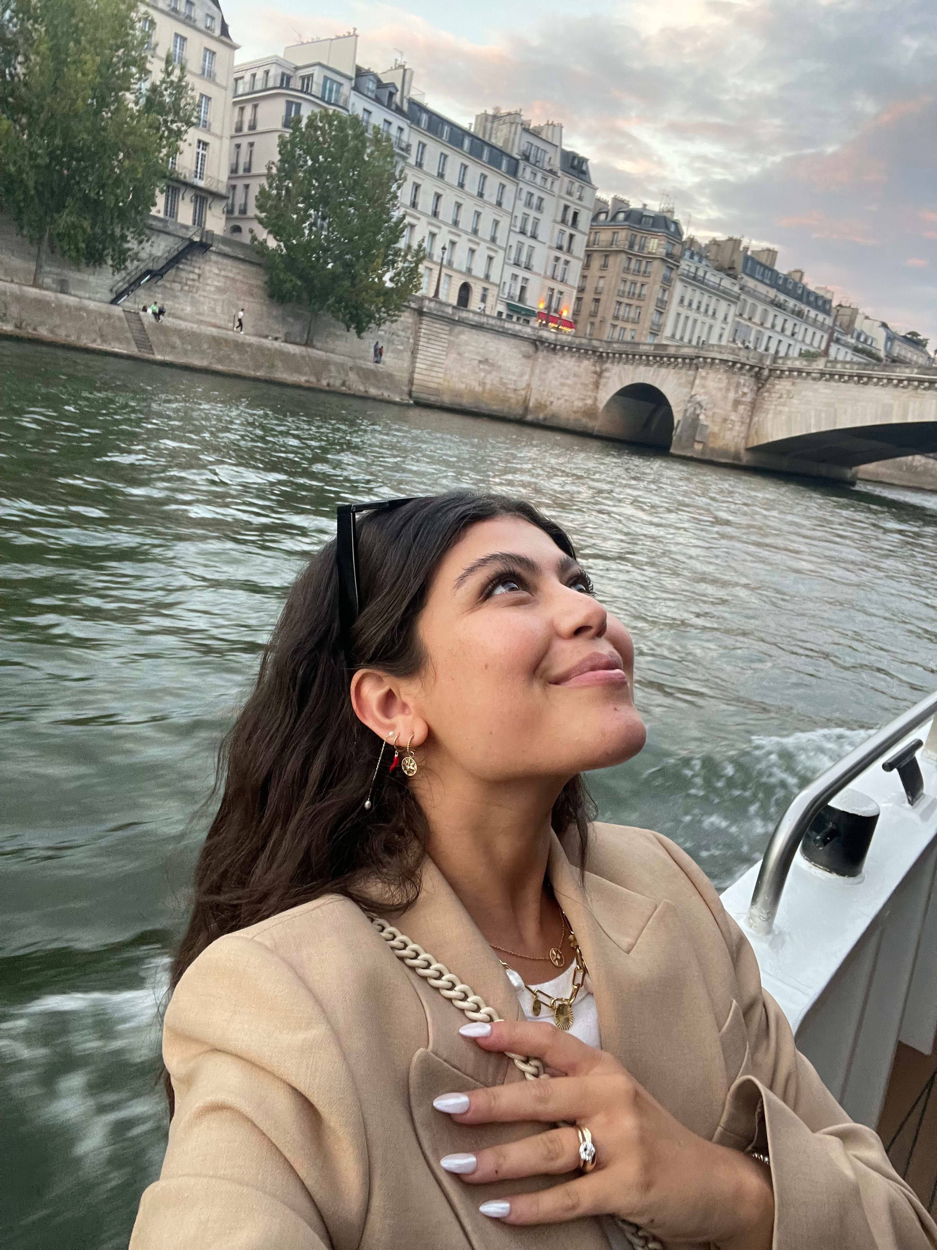 Picture of Sophie looking upwards wearing a beige coat on the Seine