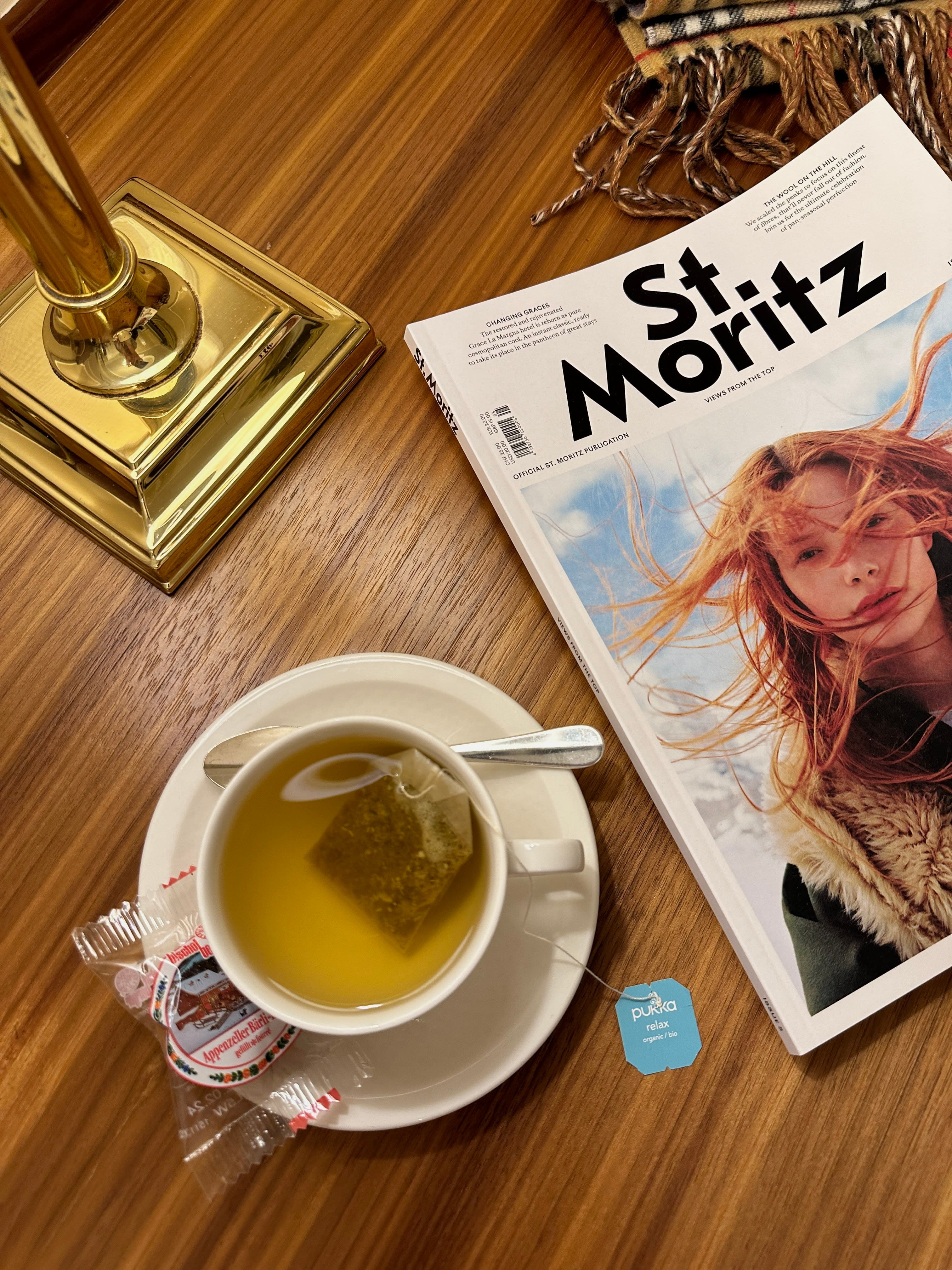 Cup of tea next to a magazine on a wooden table