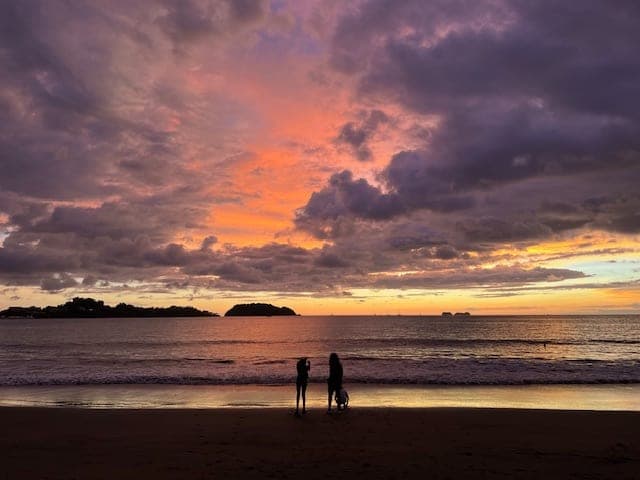 Beautiful view of a family standing in front of the ocean and colorful sky at sunset