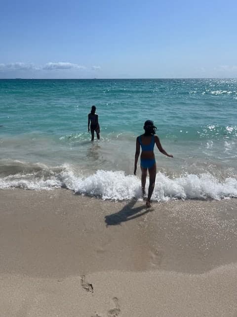 Picture of Smita and a friend wading into a turquoise ocean on a clear day