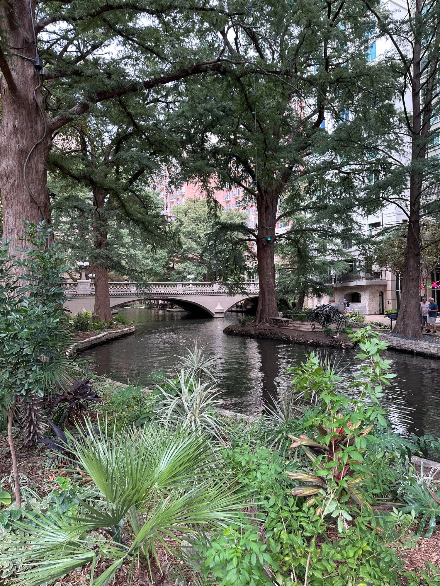 View of garden with a curved river in the center and low bridge in the distance