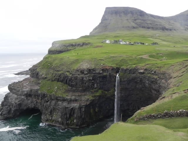 A picture of green cliffs with the ocean in view