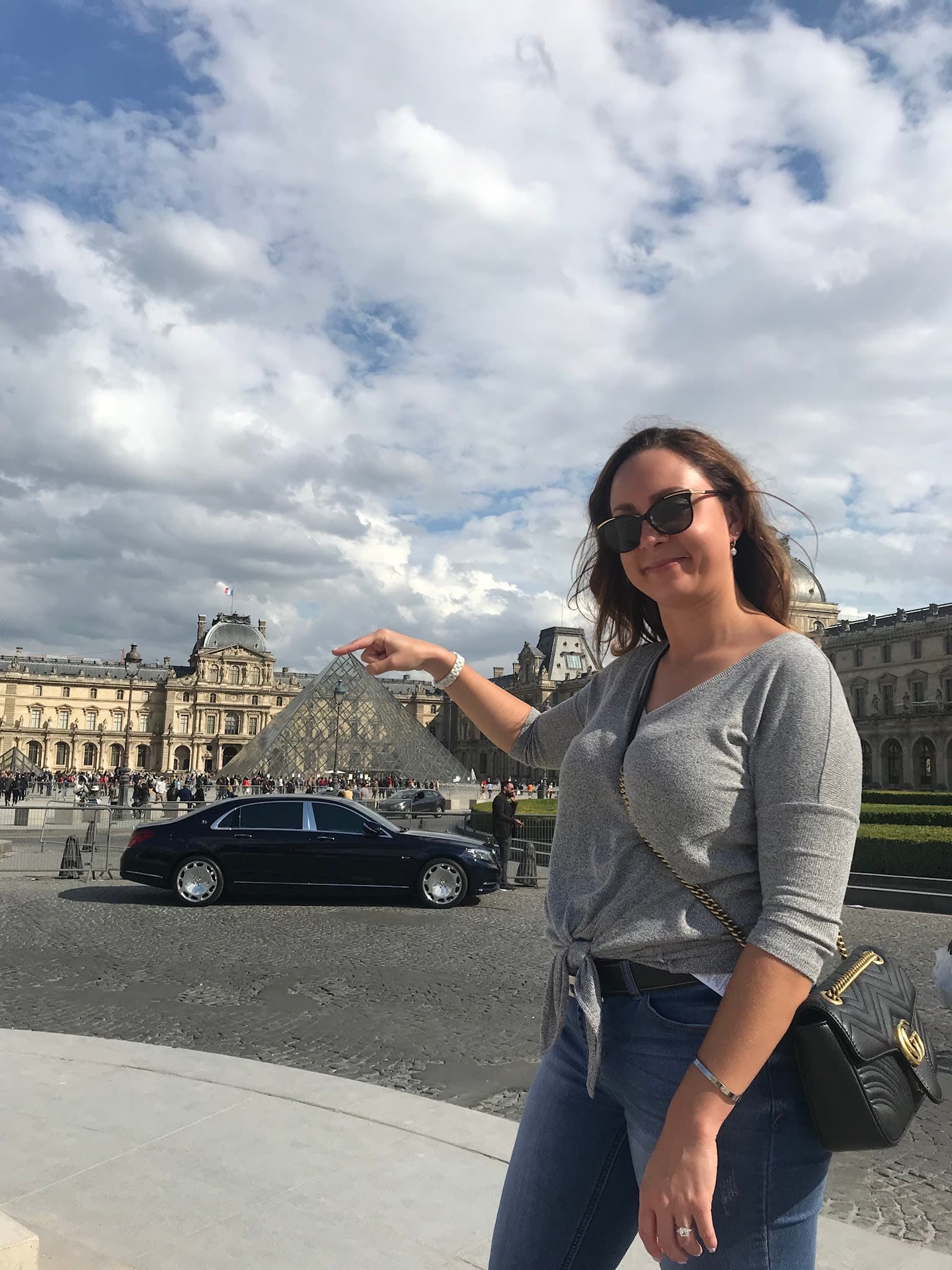 Megan posing in front of the Louvre with her hand positioned to look like she's holding it.