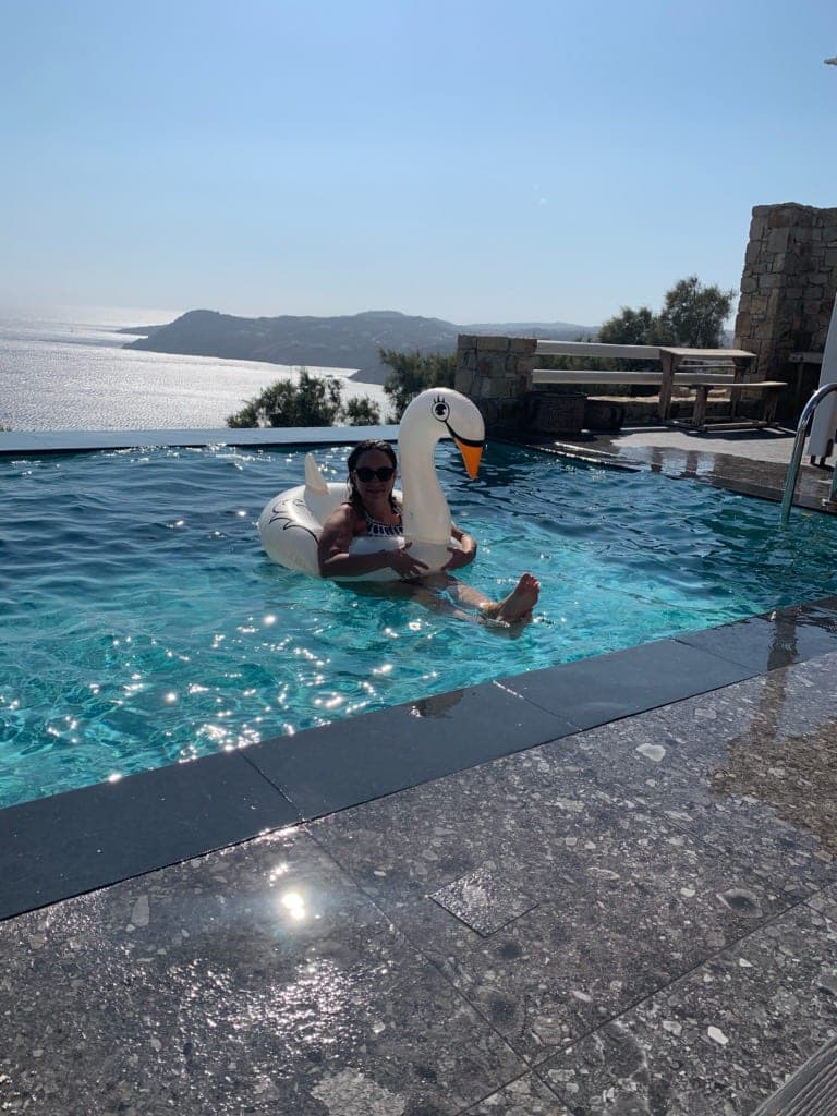Megan on an inflatable swan in an infinity pool overlooking the ocean.