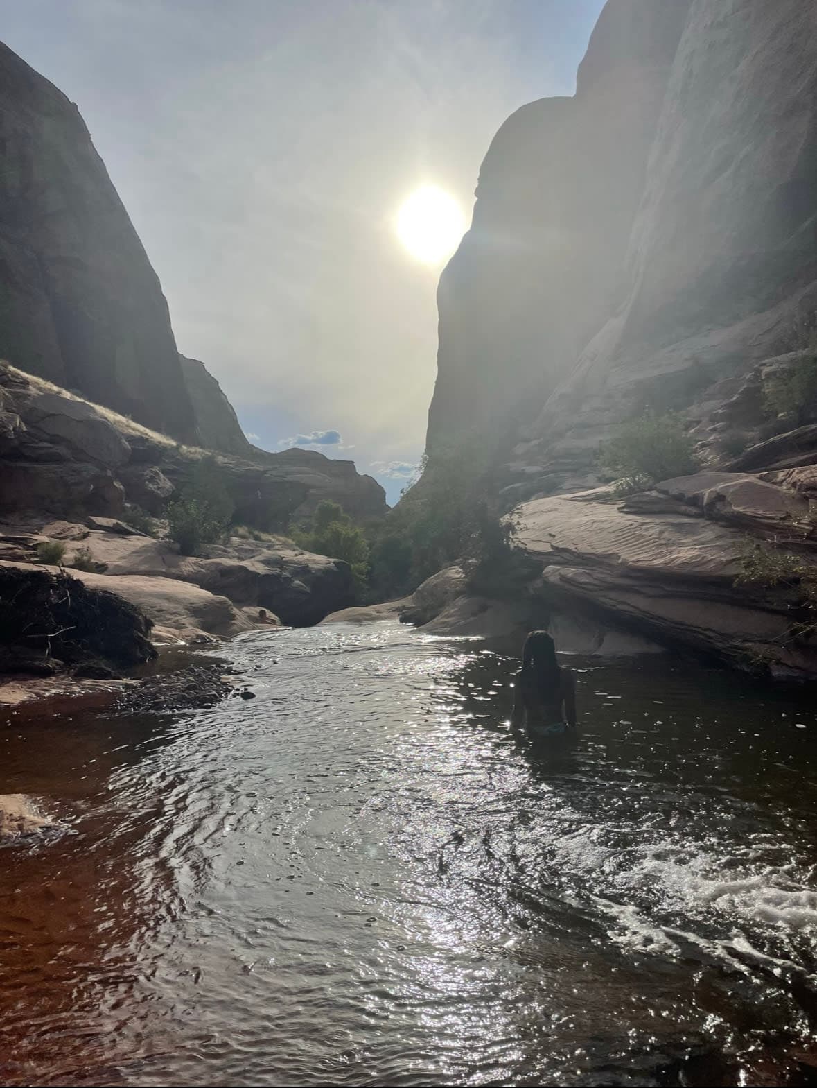 A girl in a bathing suit standing in a river running through a rock canyon.