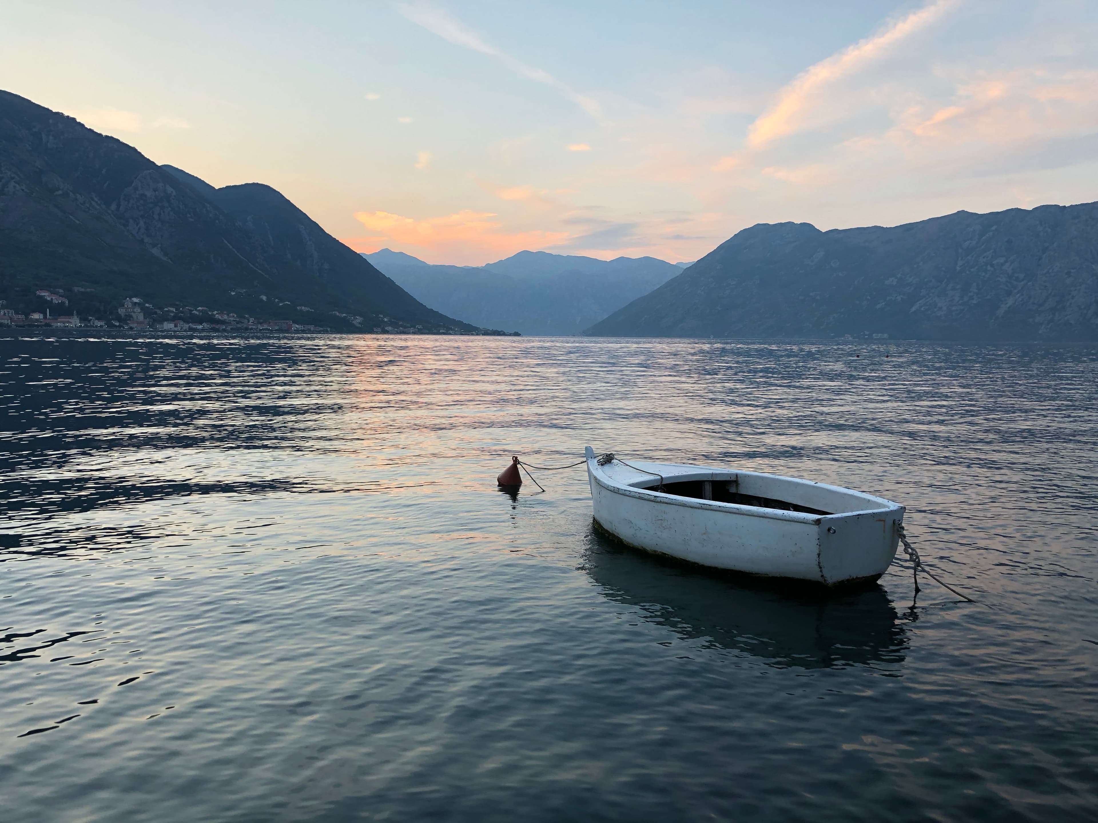 Beautiful view of lake surrounded by mountains with a small empty boat in the foreground