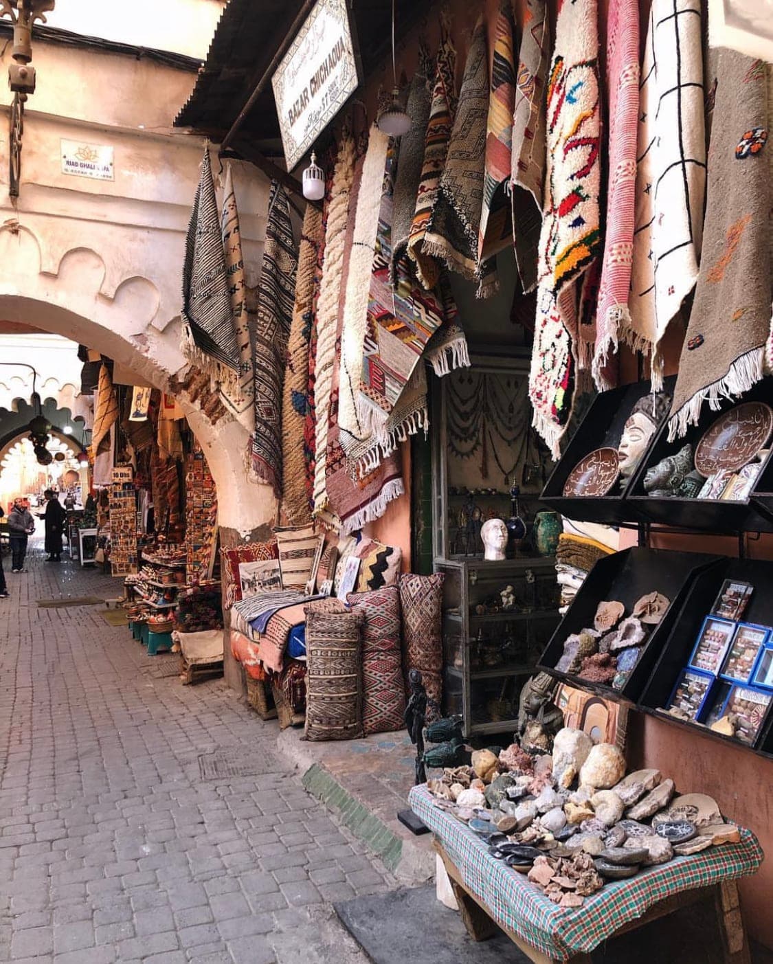 View of a street full of vendor stalls displaying colorful hanging rugs and other local items