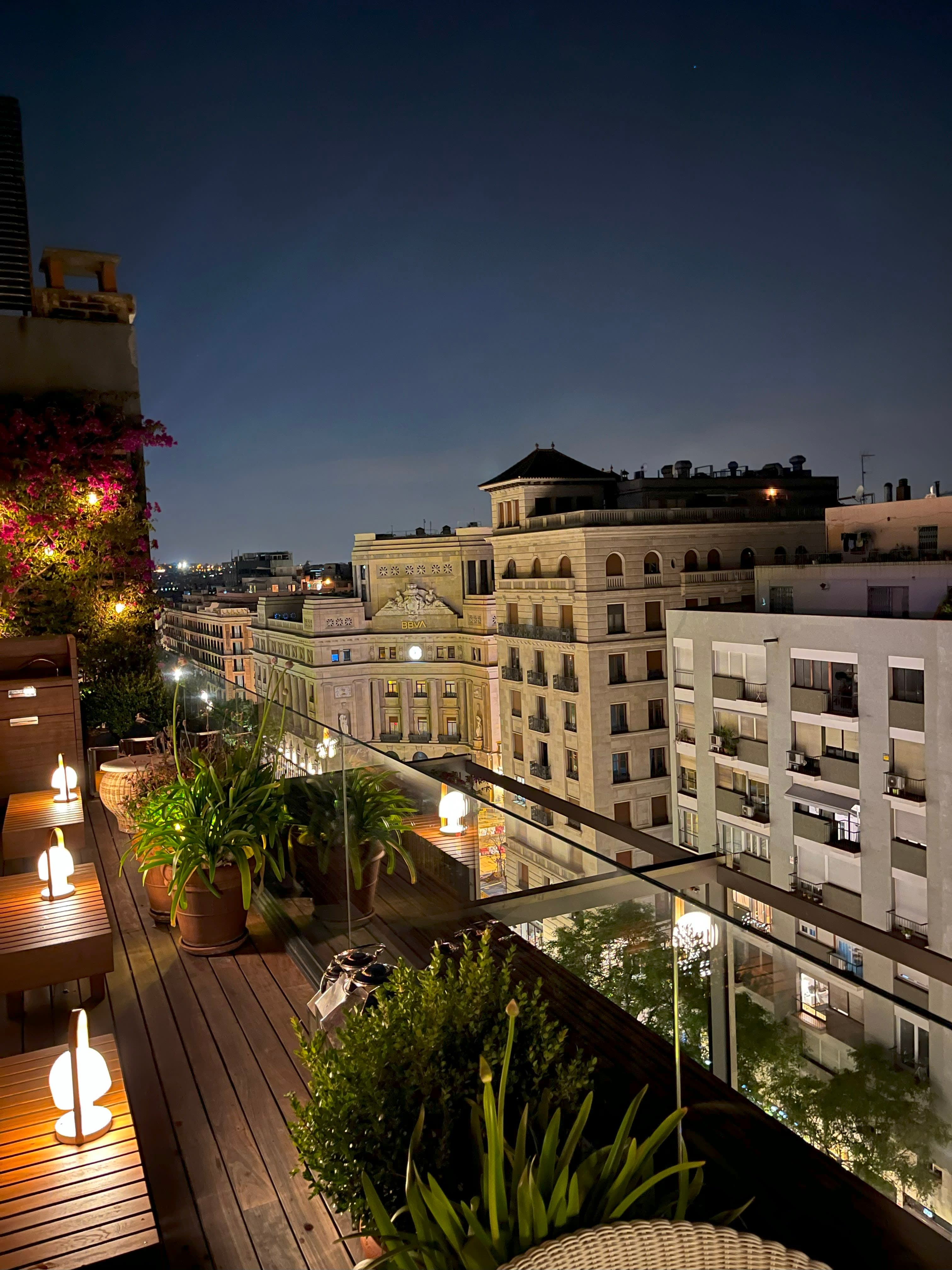 View of buildings from a balcony with plants at The Barcelona EDITION hotel at night