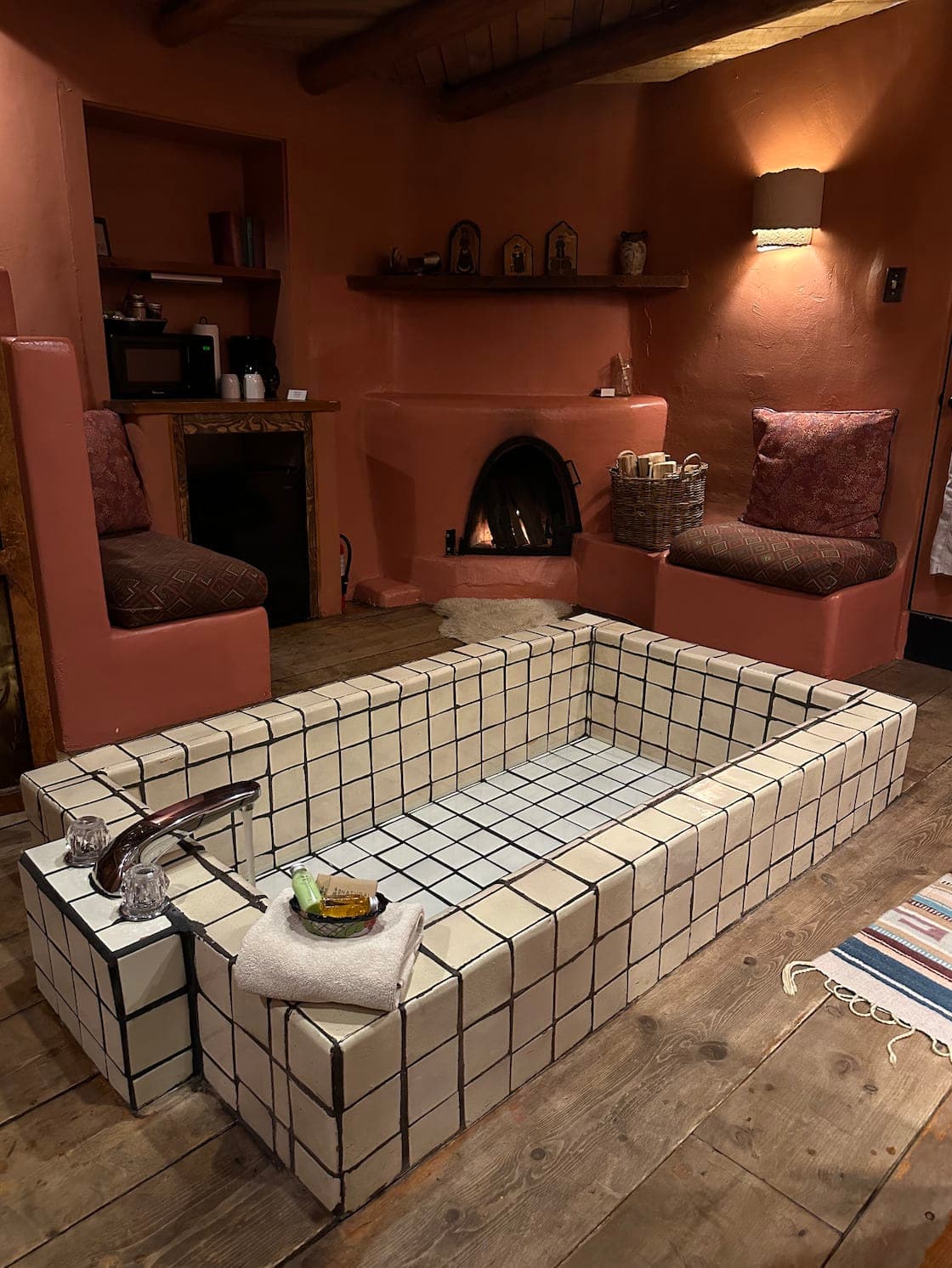 View of a large white-tiled bathtub in a cozy bathroom