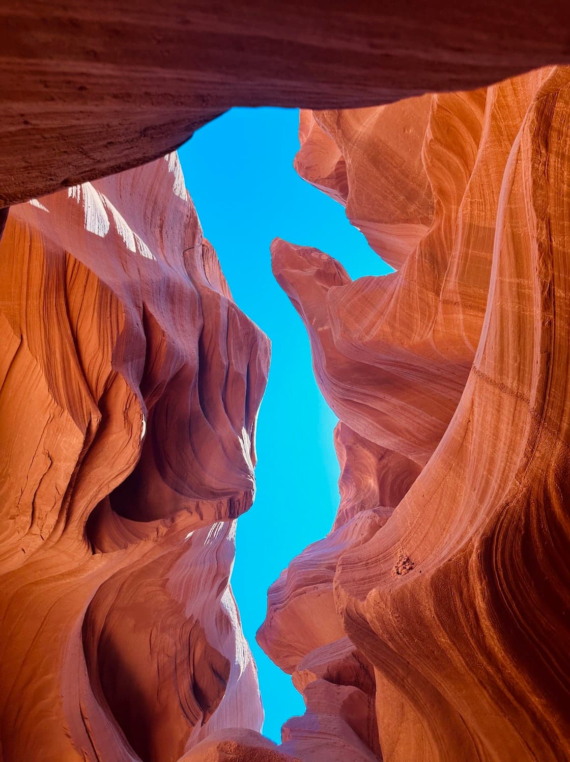 Beautiful view of a sliver of bright blue sky in between rock formations in Antelope Canyon