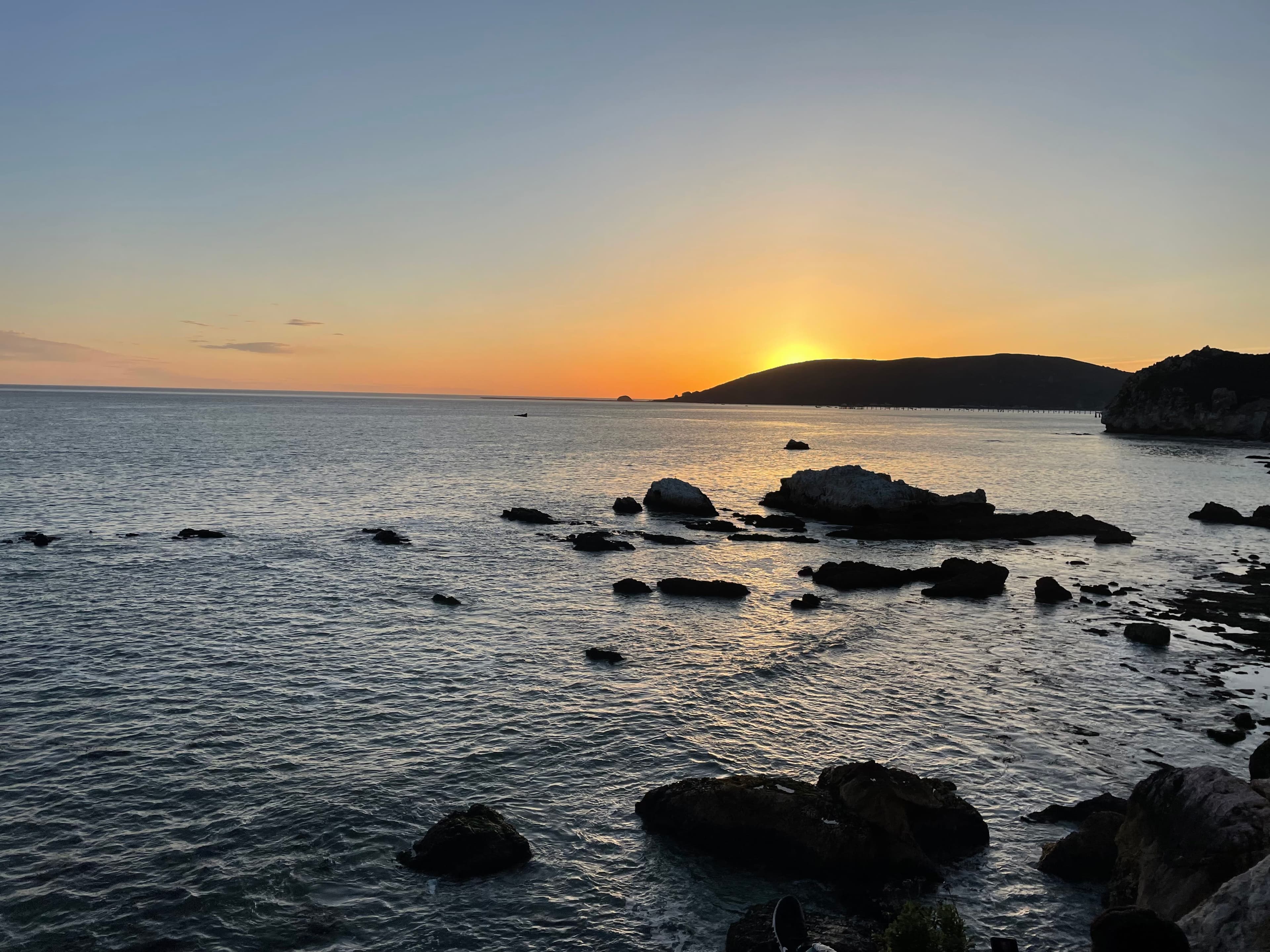 Beautiful view of sunset over a calm ocean seascape dotted with rocks