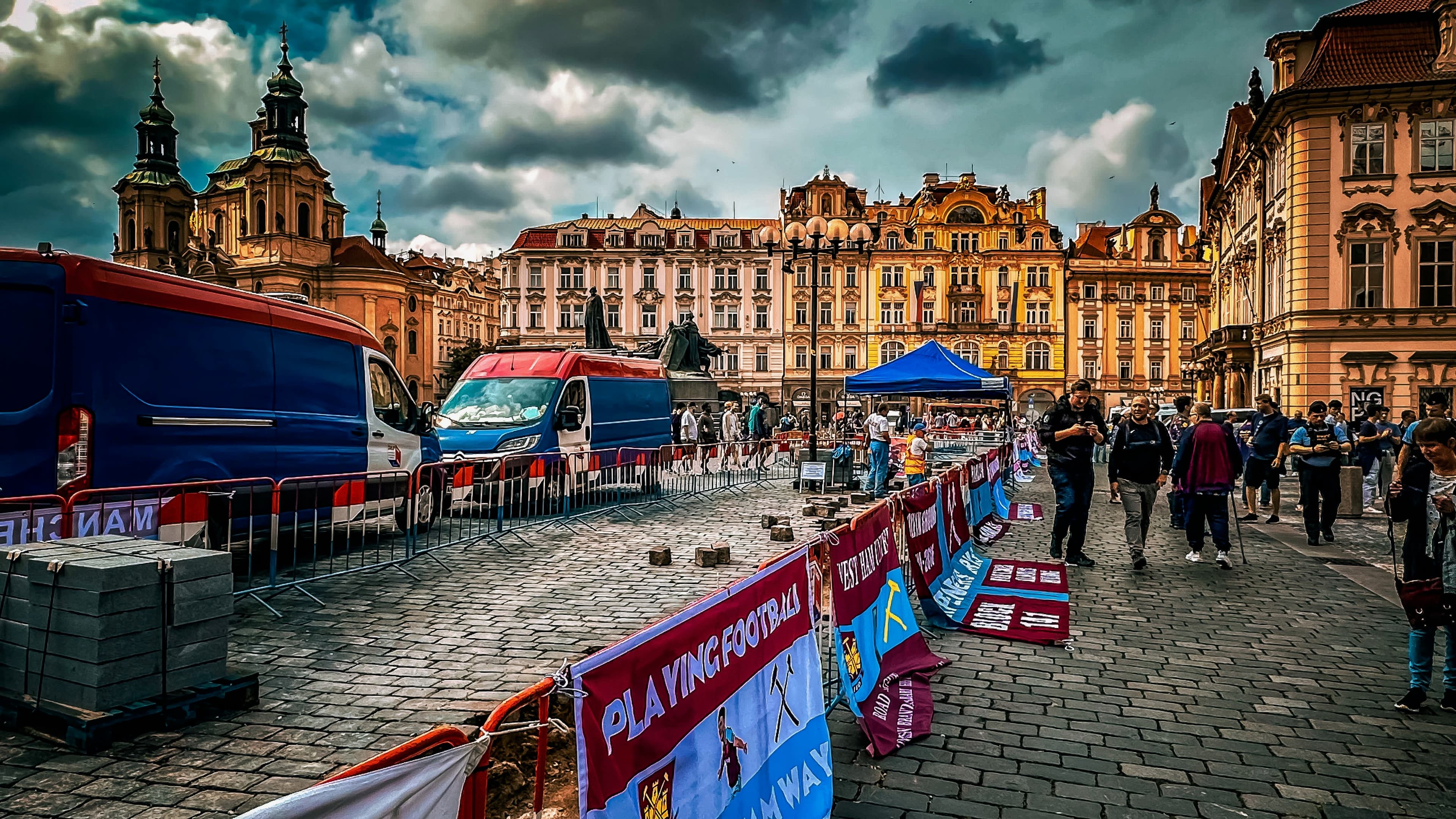 View of Old Town Square with busses and pedestrians passing in front of beautiful, large buildings