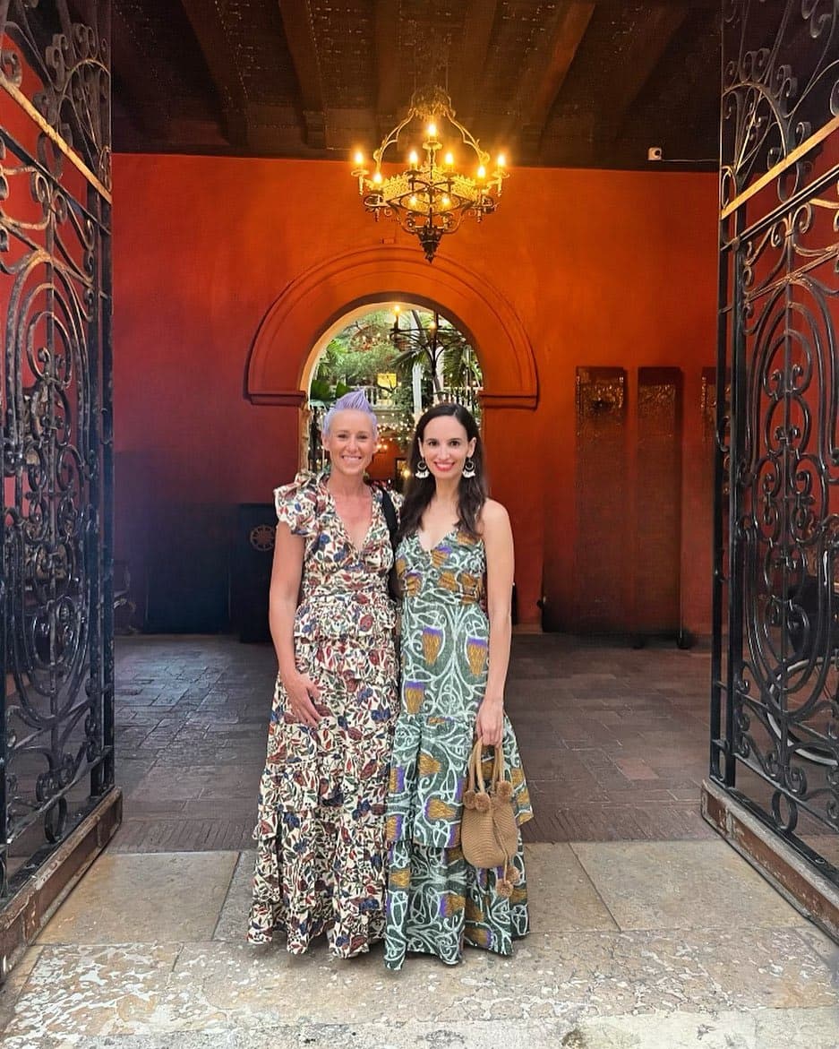 Picture of Mindy and a friend wearing long colorful dresses and smiling for the camera