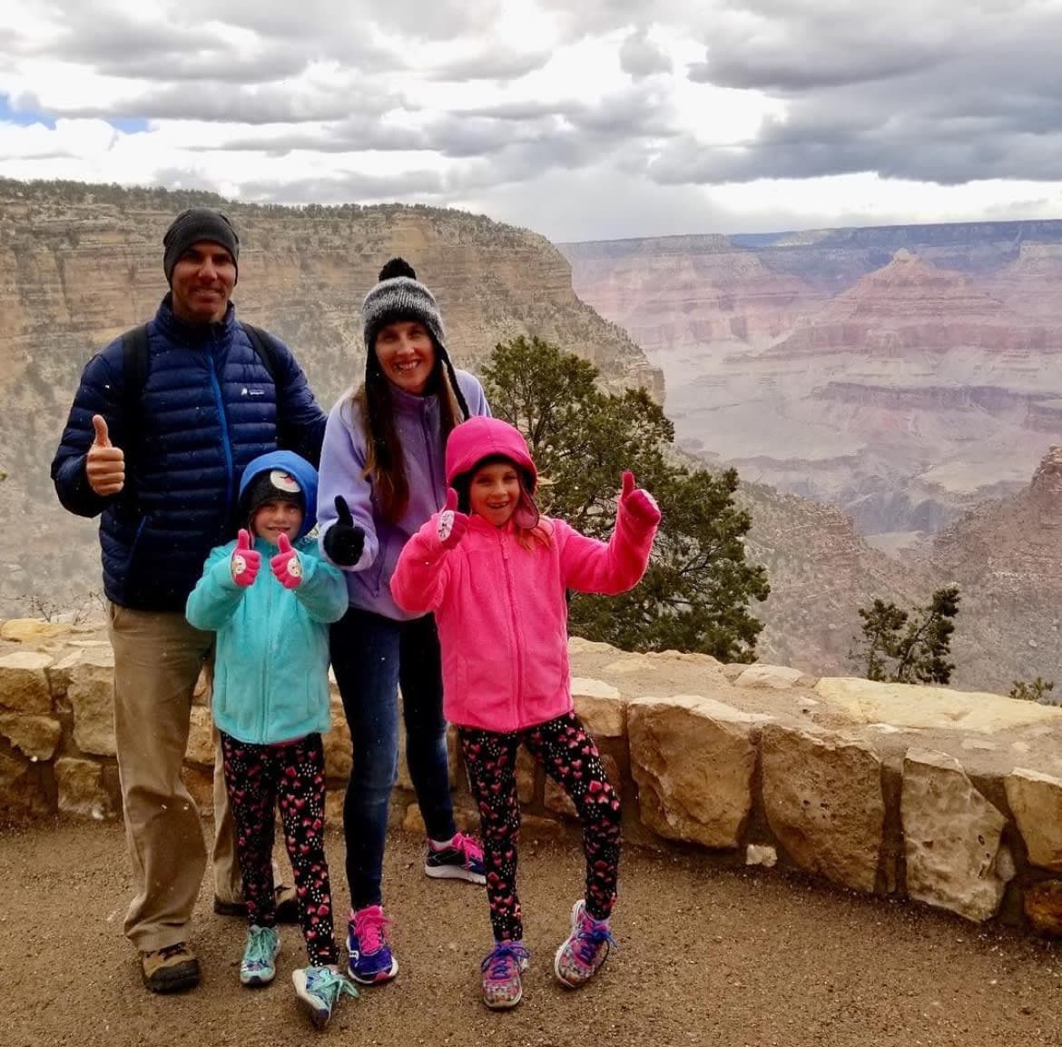 Picture of Jill with her family at Grand Canyon National Park posing with thumbs up on a cloudy day
