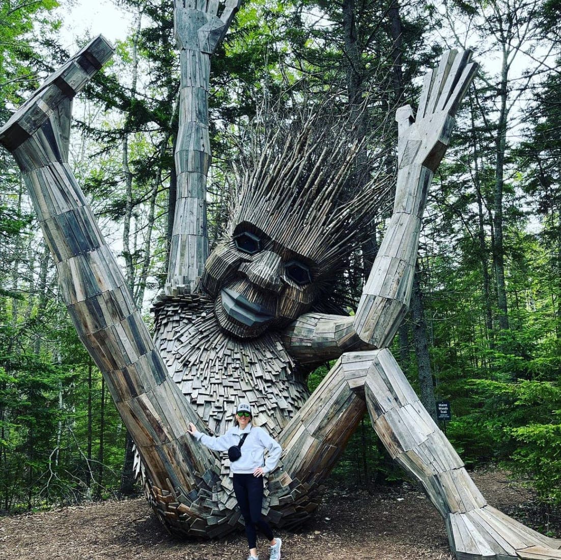 Picture of Jill at Coastal Maine Botanical Gardens in front of a large human-like wooden sculpture