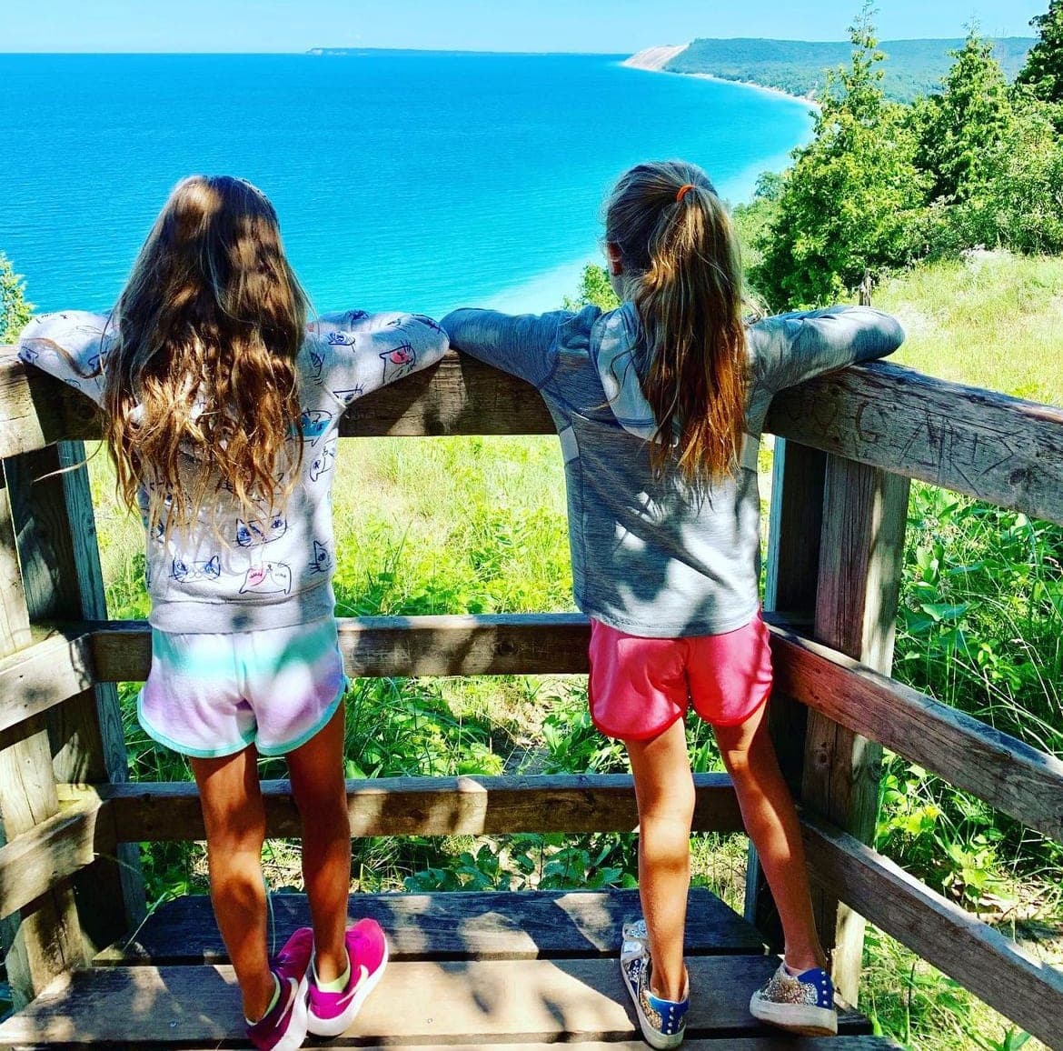 Picture of two young girls looking out over a beautiful sea view on a sunny day