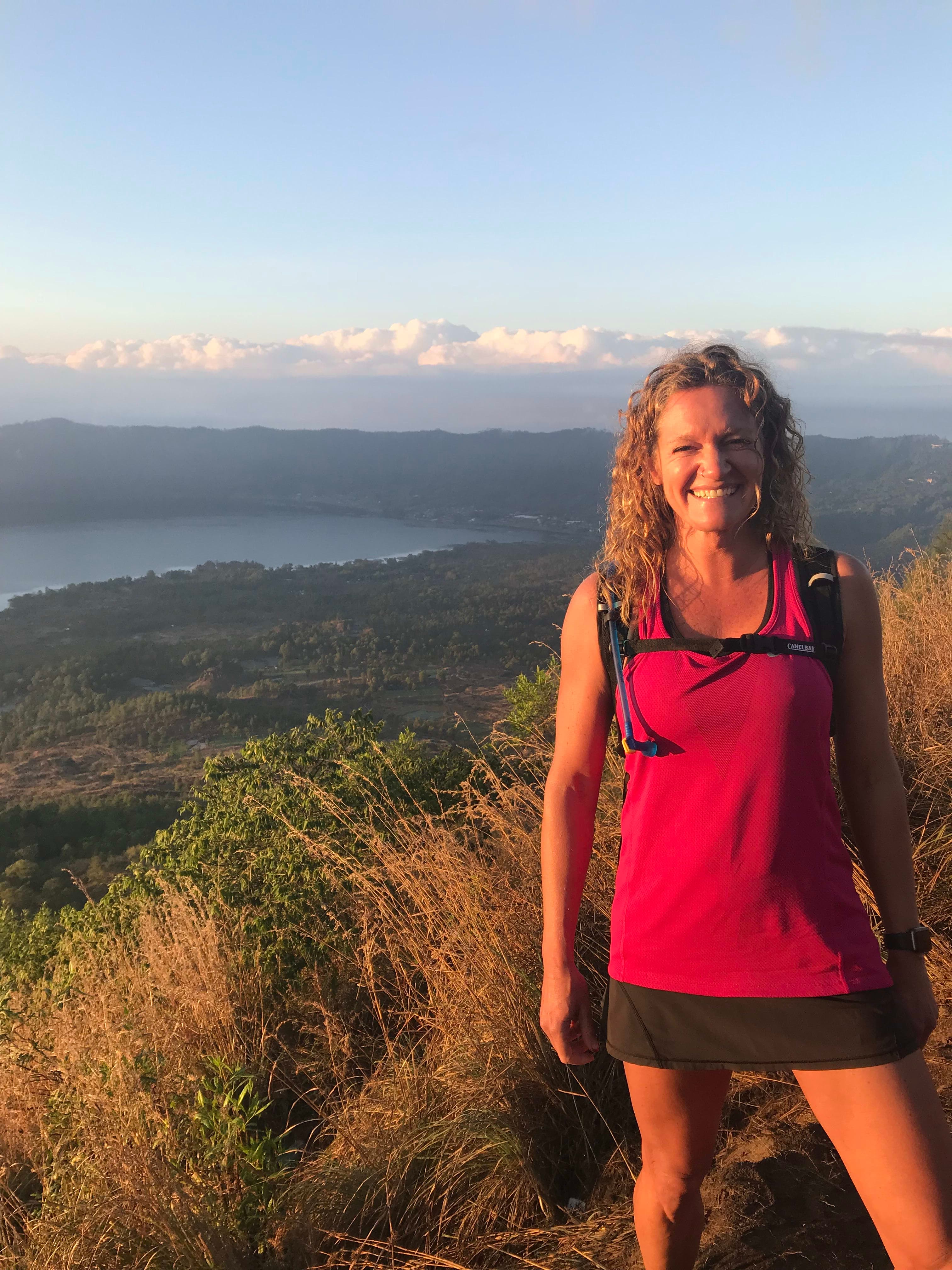 Picture of Dayna on a hike with a beautiful view of the sea and mountains in the background