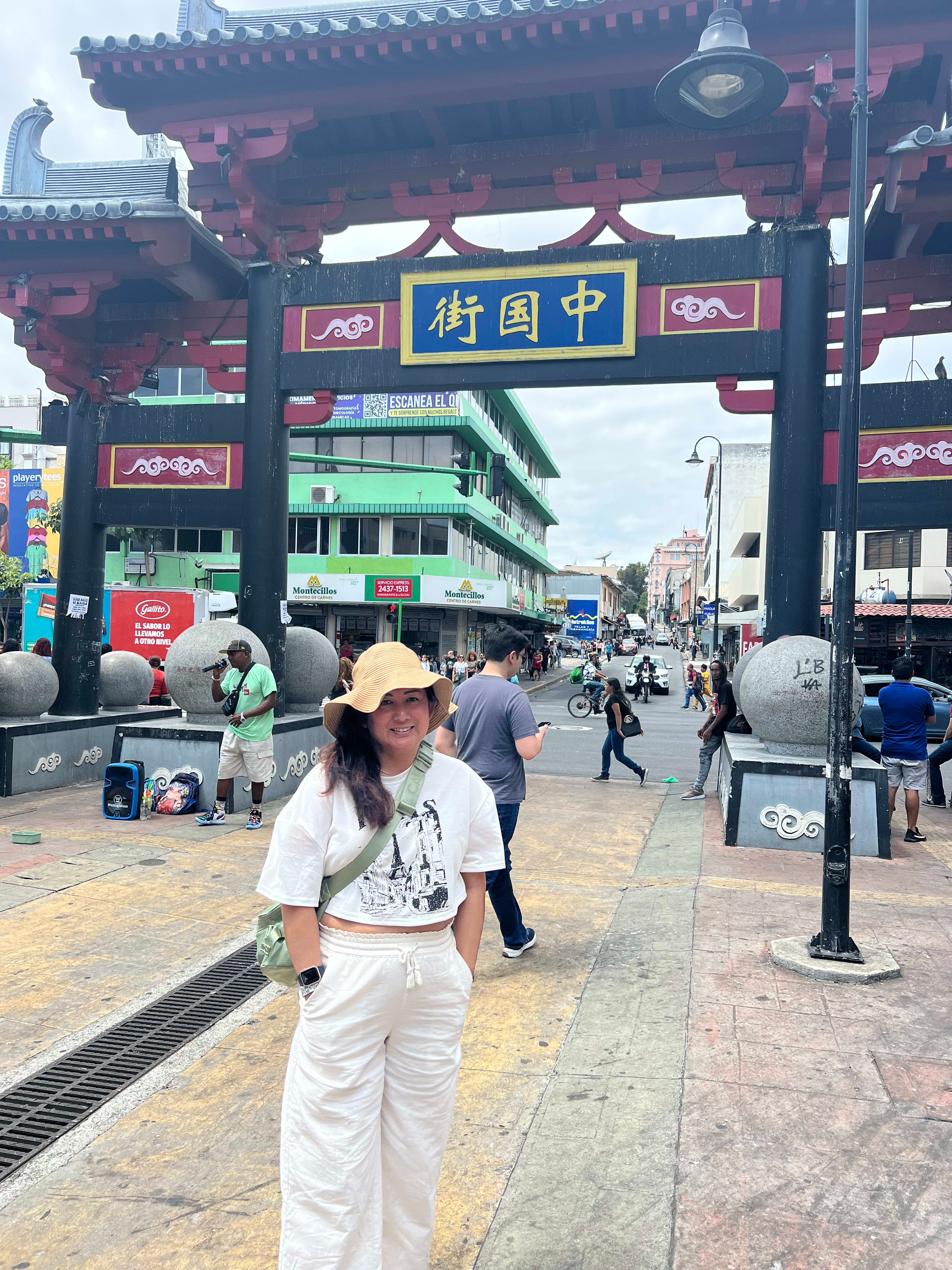 Picture of Hazel wearing a hat and posing on a mostly empty street in China