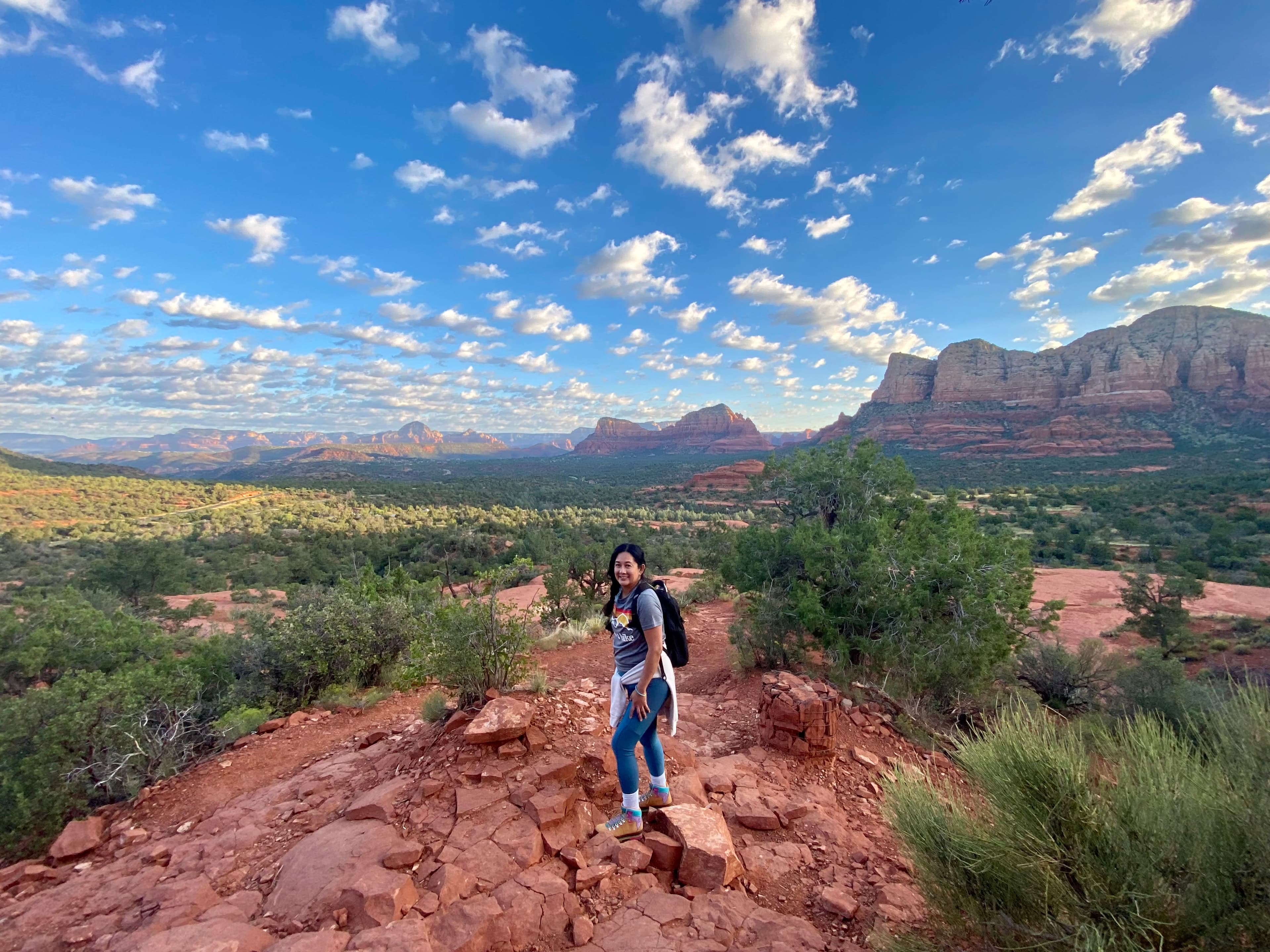 Picture of Hazel hiking on a sunny day with a beautiful view of a green valley and rock formations in the distance