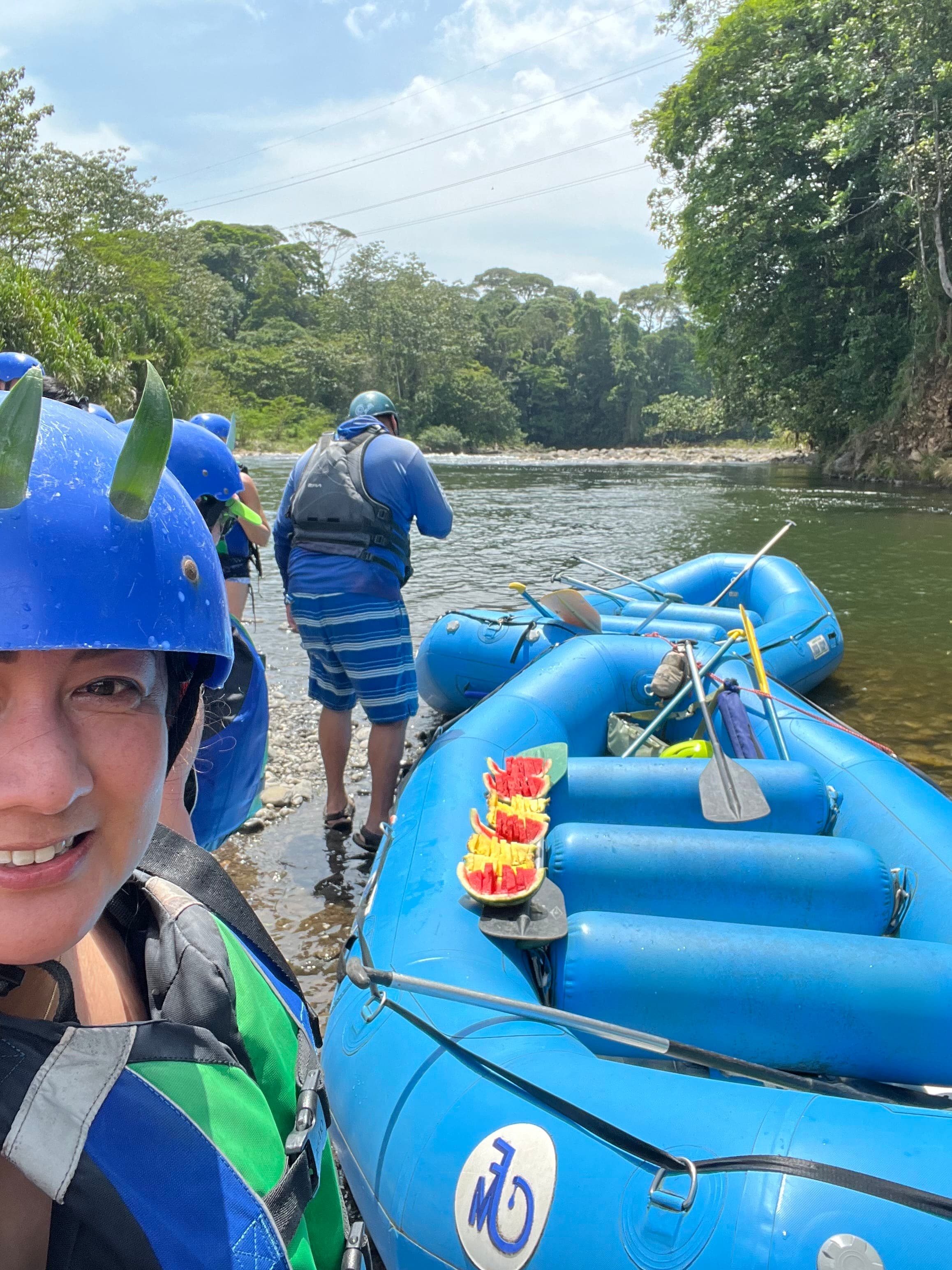 Picture of Hazel taking a selfie in a blue helmet before going rafting on a tree-lined river