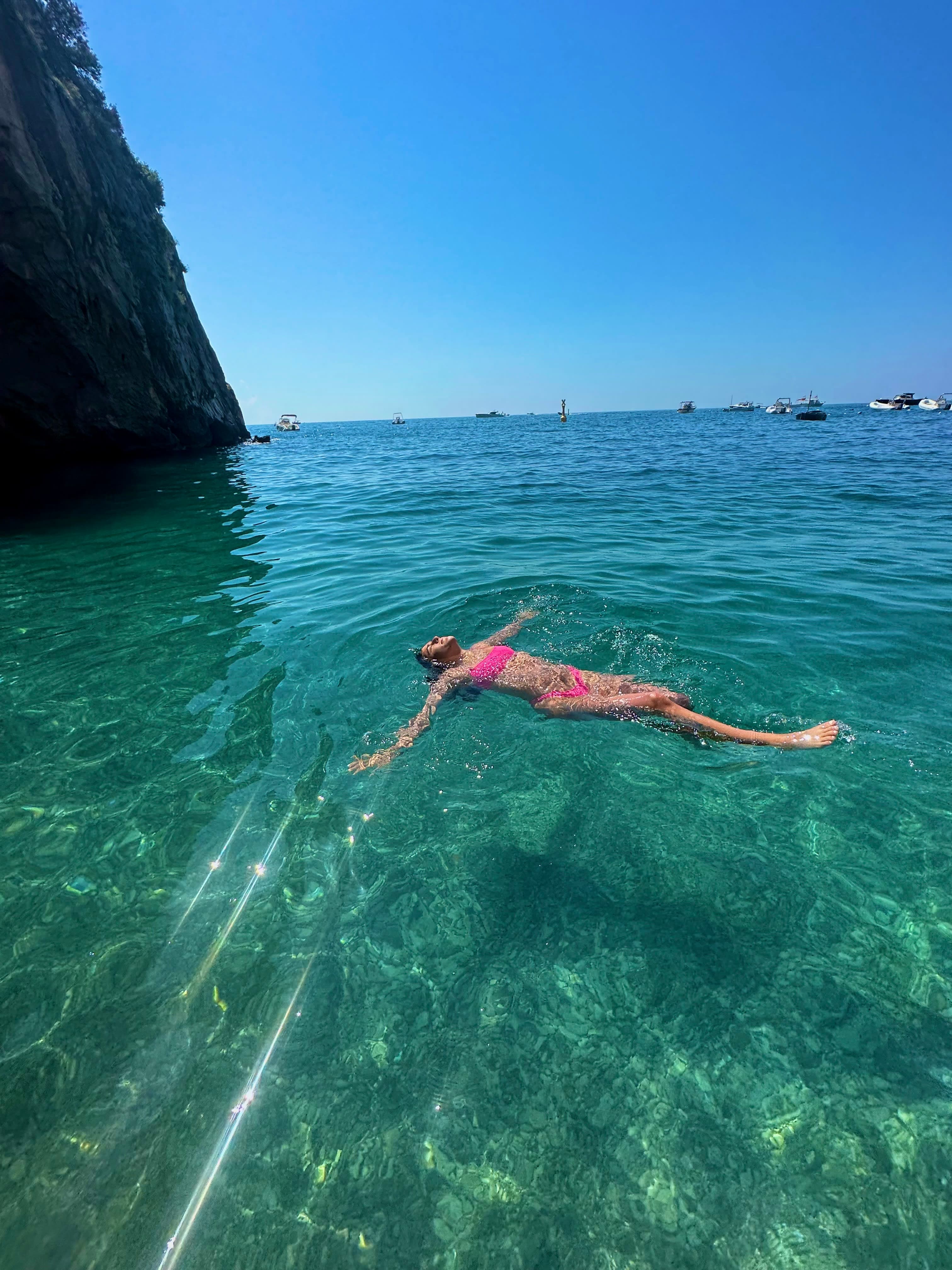 Avery in a pink swimsuit floating in the clear blue water of the sea