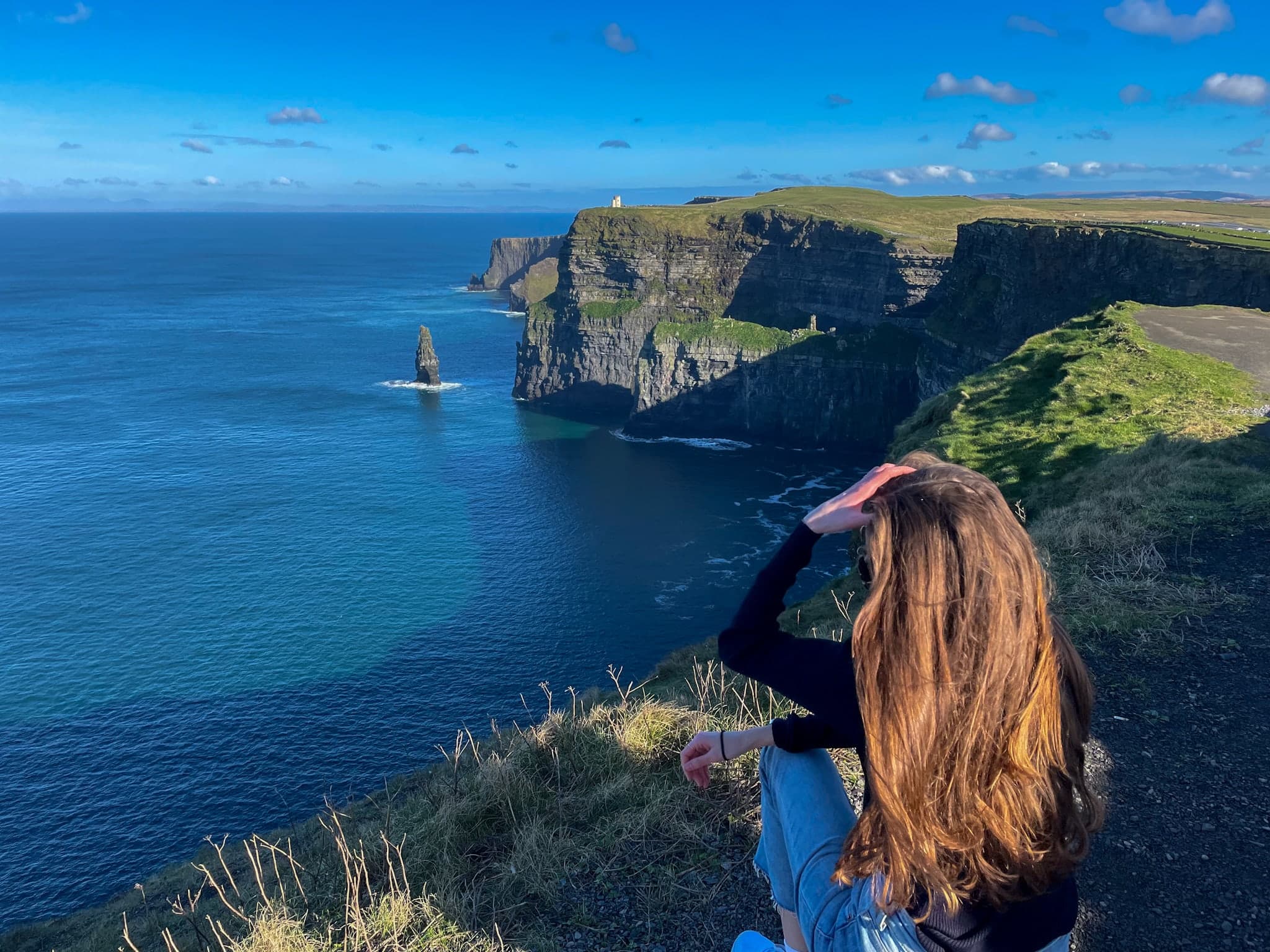 Ashley sitting on the ground and looking at the beautiful view of the sea