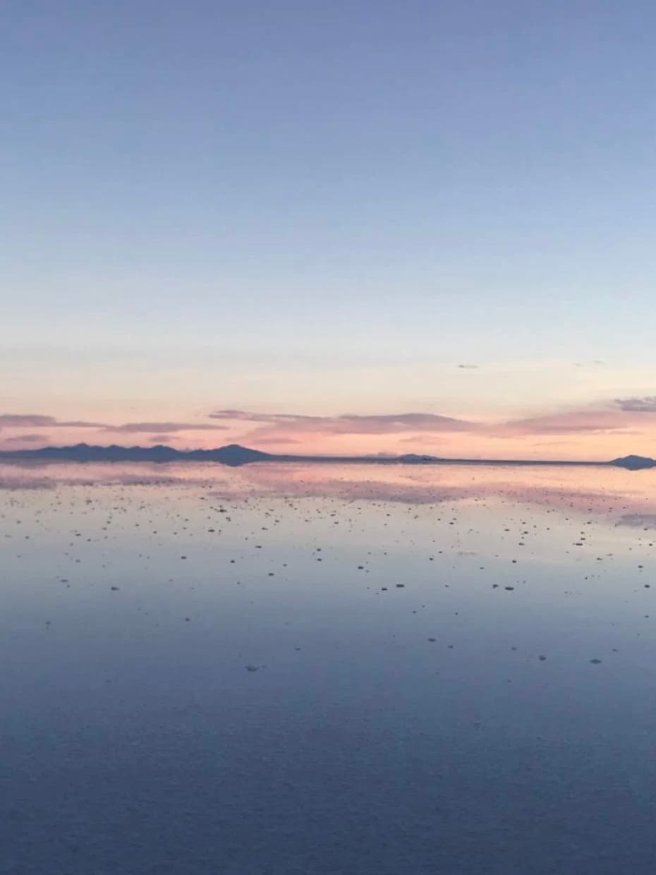 Beautiful view of a glassy lake reflecting the light blue sky with mountains on the distant horizon