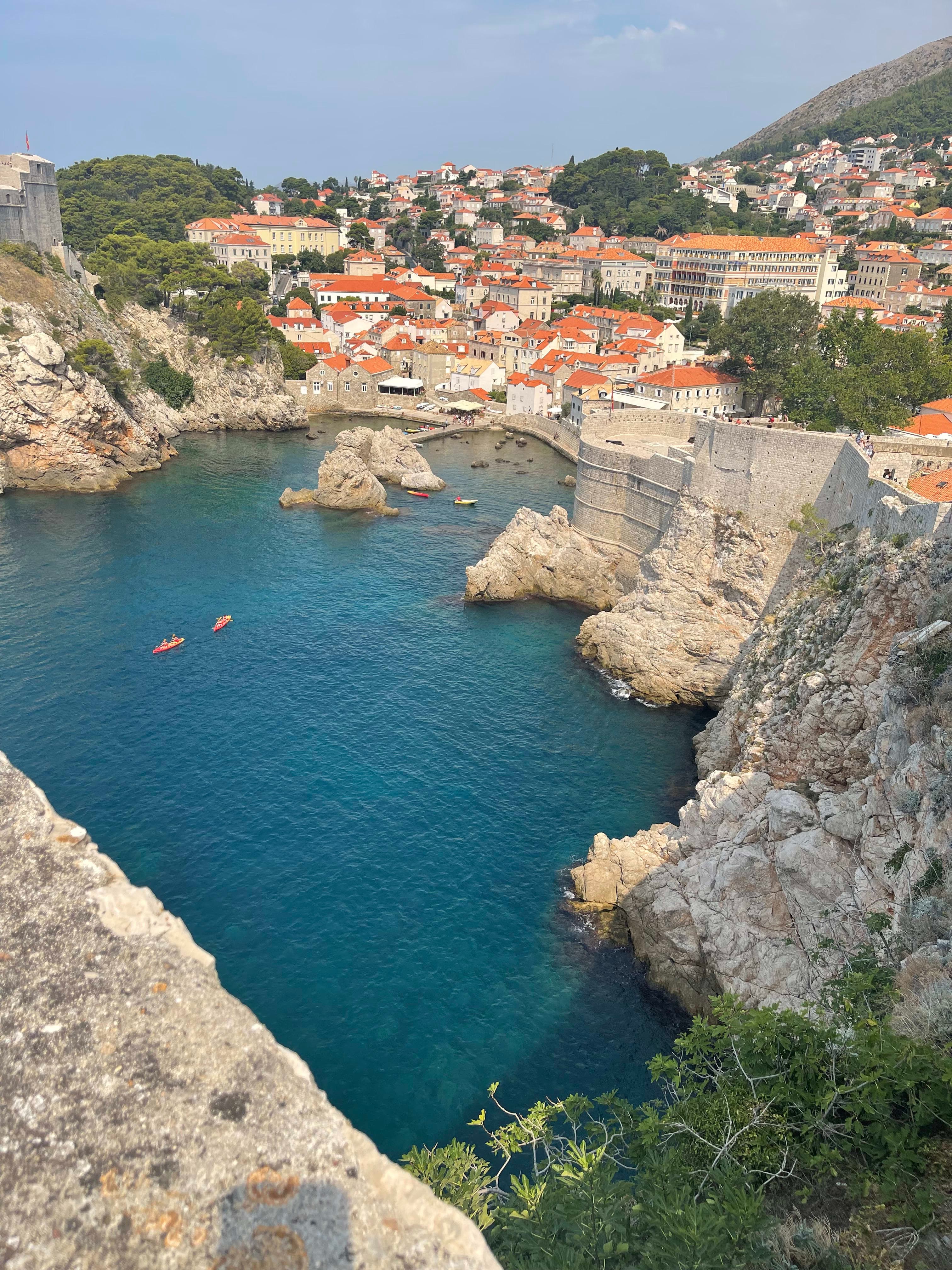 Aerial view of a walled Croatian city with orange rooftops on a beautiful blue bay