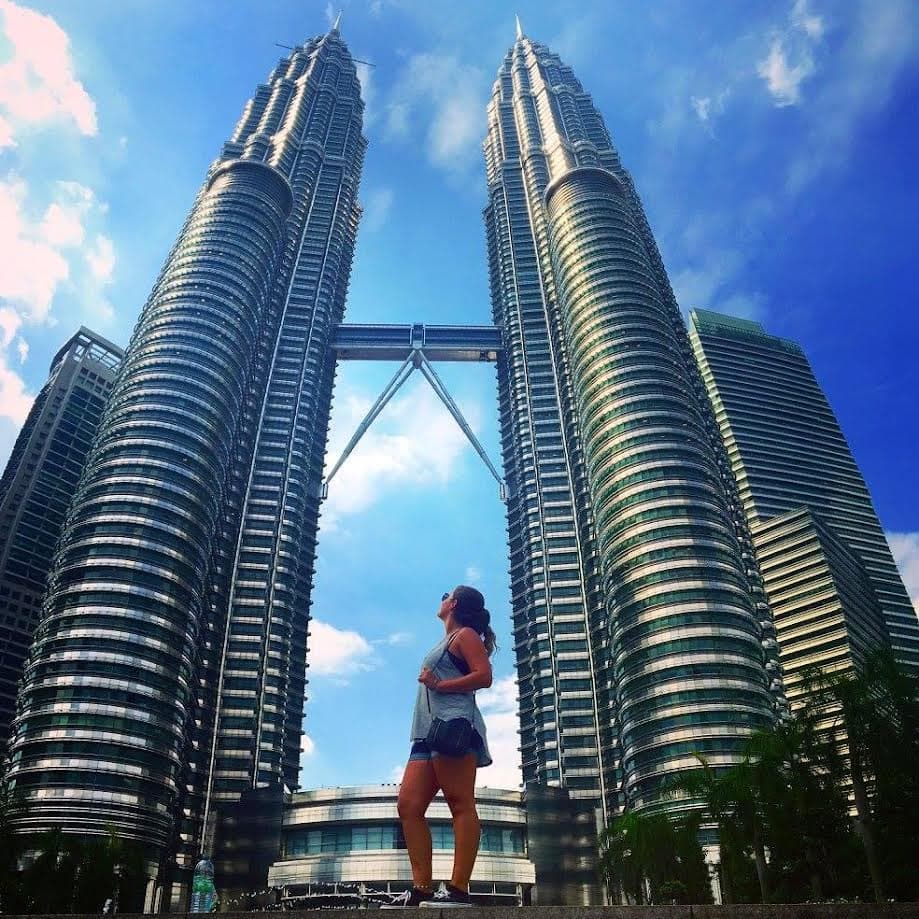 Brianna posing for a photo looking up at the Petronas Twin Towers on a sunny day