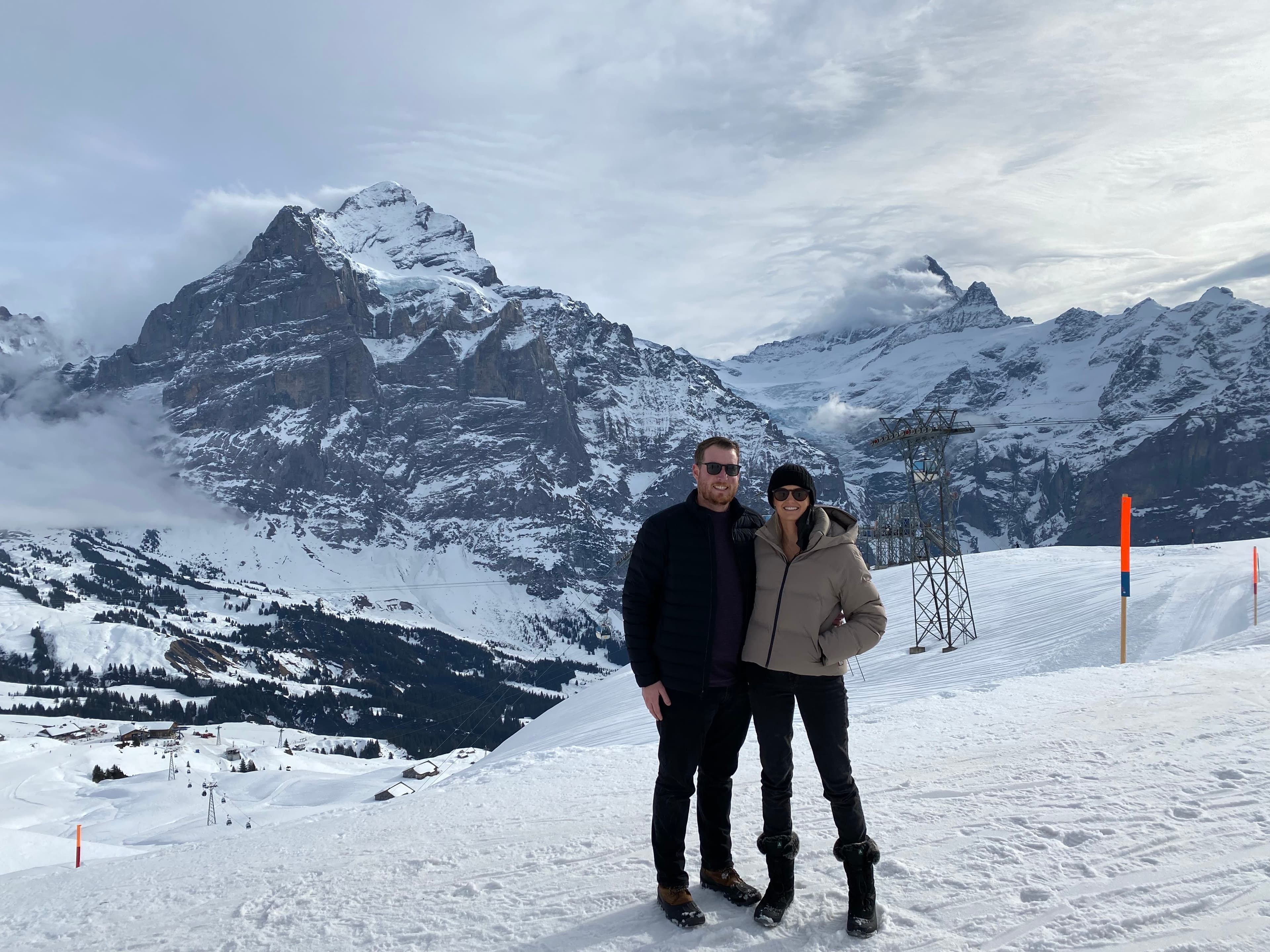 Advisor posing in front of snow-capped mountains on a cloudy day.
