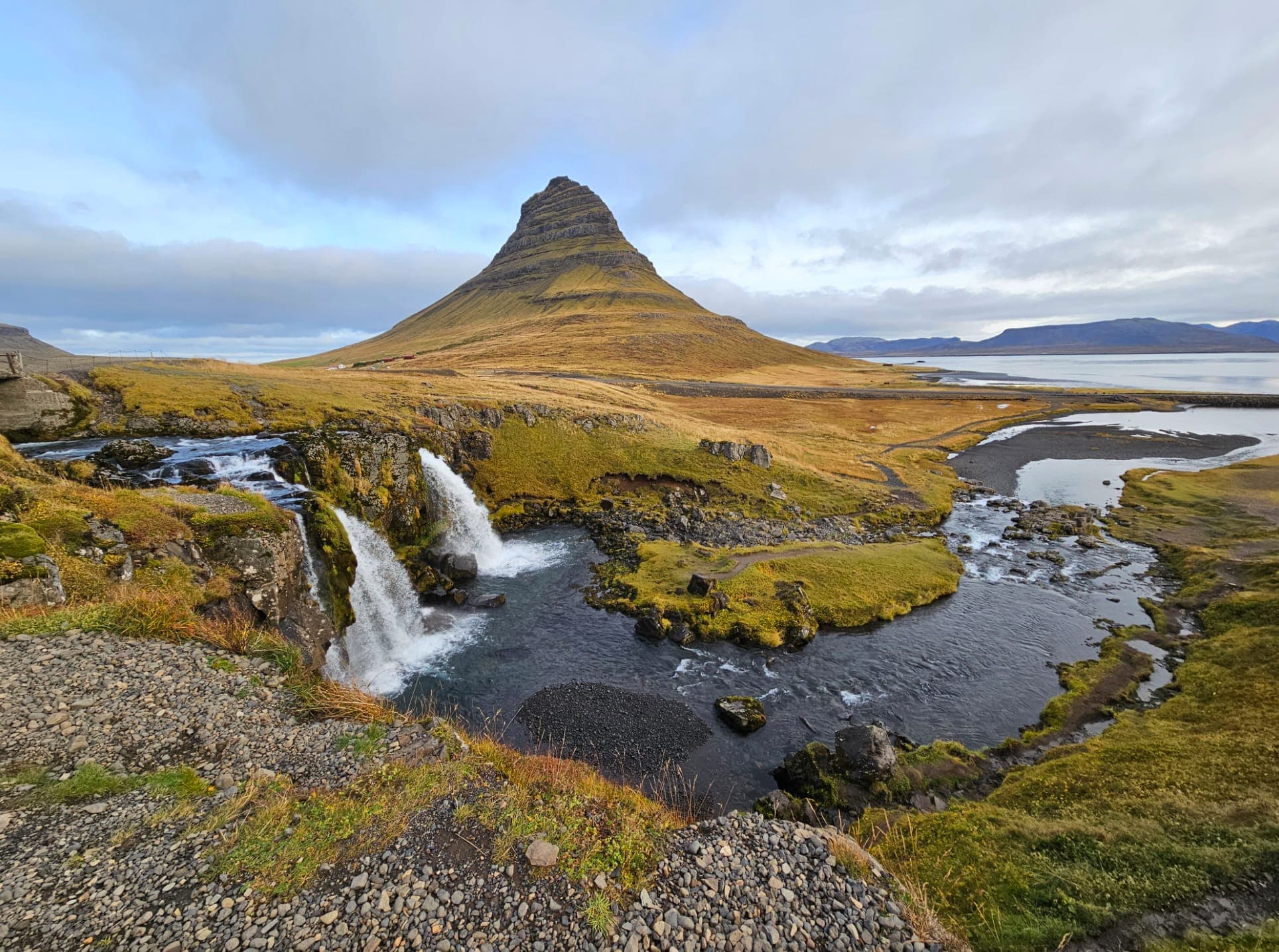 Green hills and waterfalls over a lake.