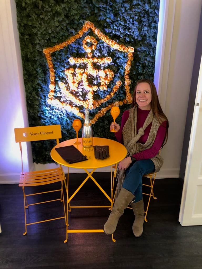 Advisor posing with a cocktail at a table inside.