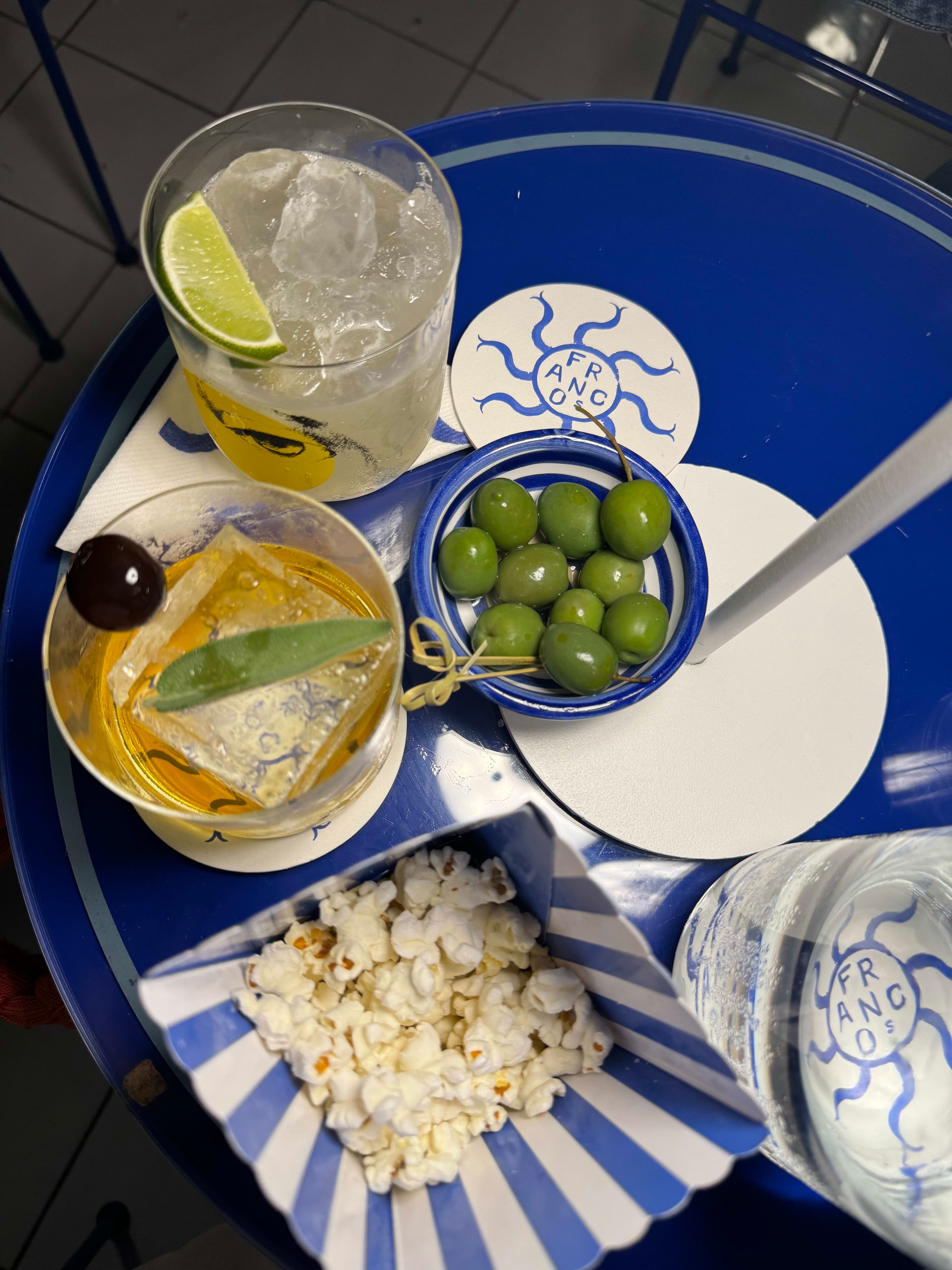 Advisor sitting outdoors holding a glass with yellow straw and purple flowers in bloom in the background