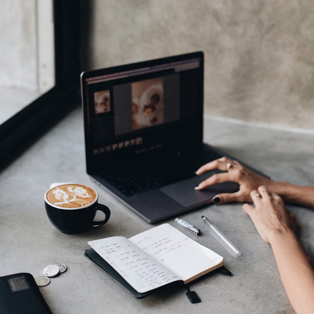 a woman in a gray sweater works on her laptop in a white room
