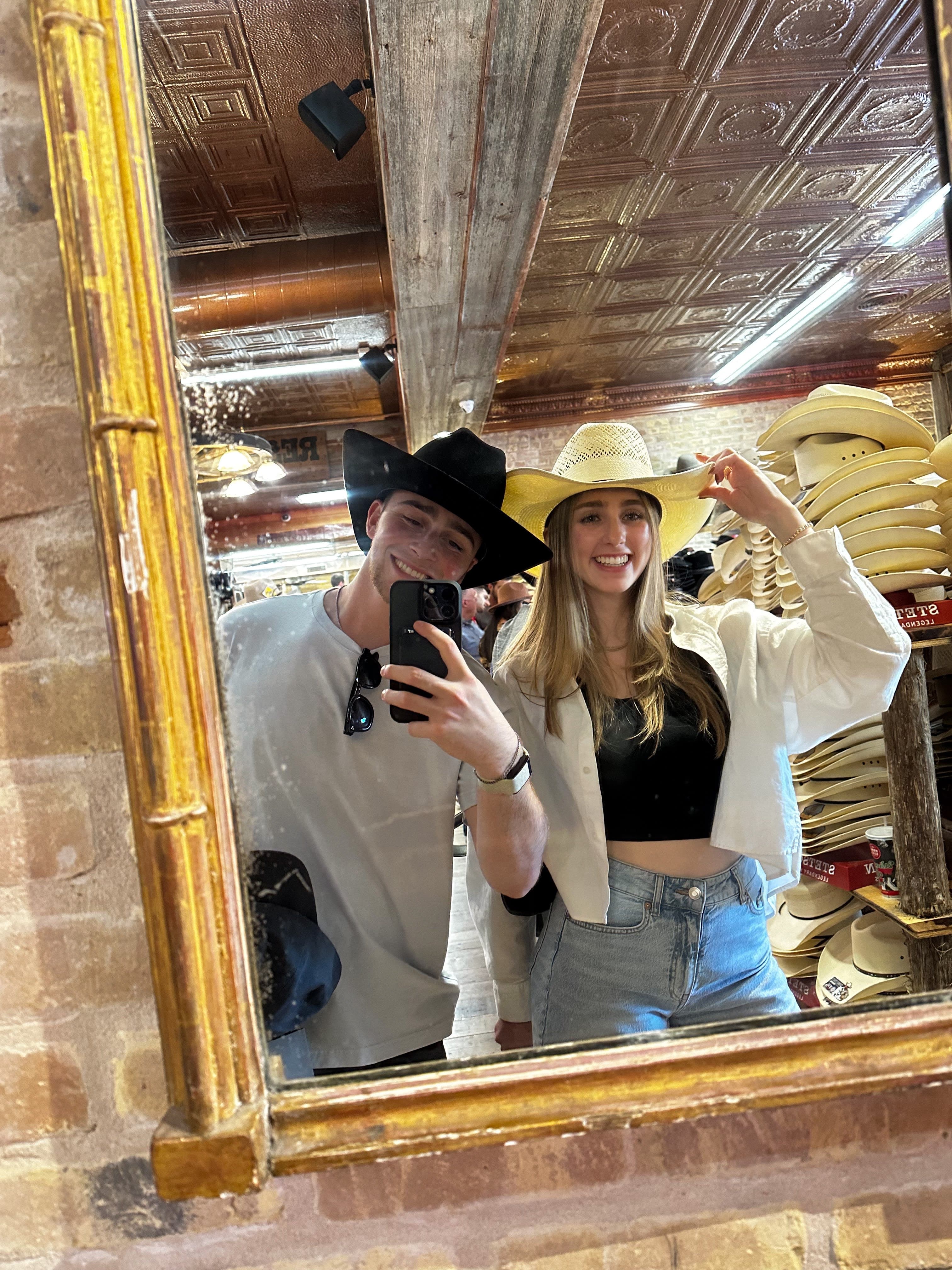 Couple posing in a mirror while wearing cowboy hats