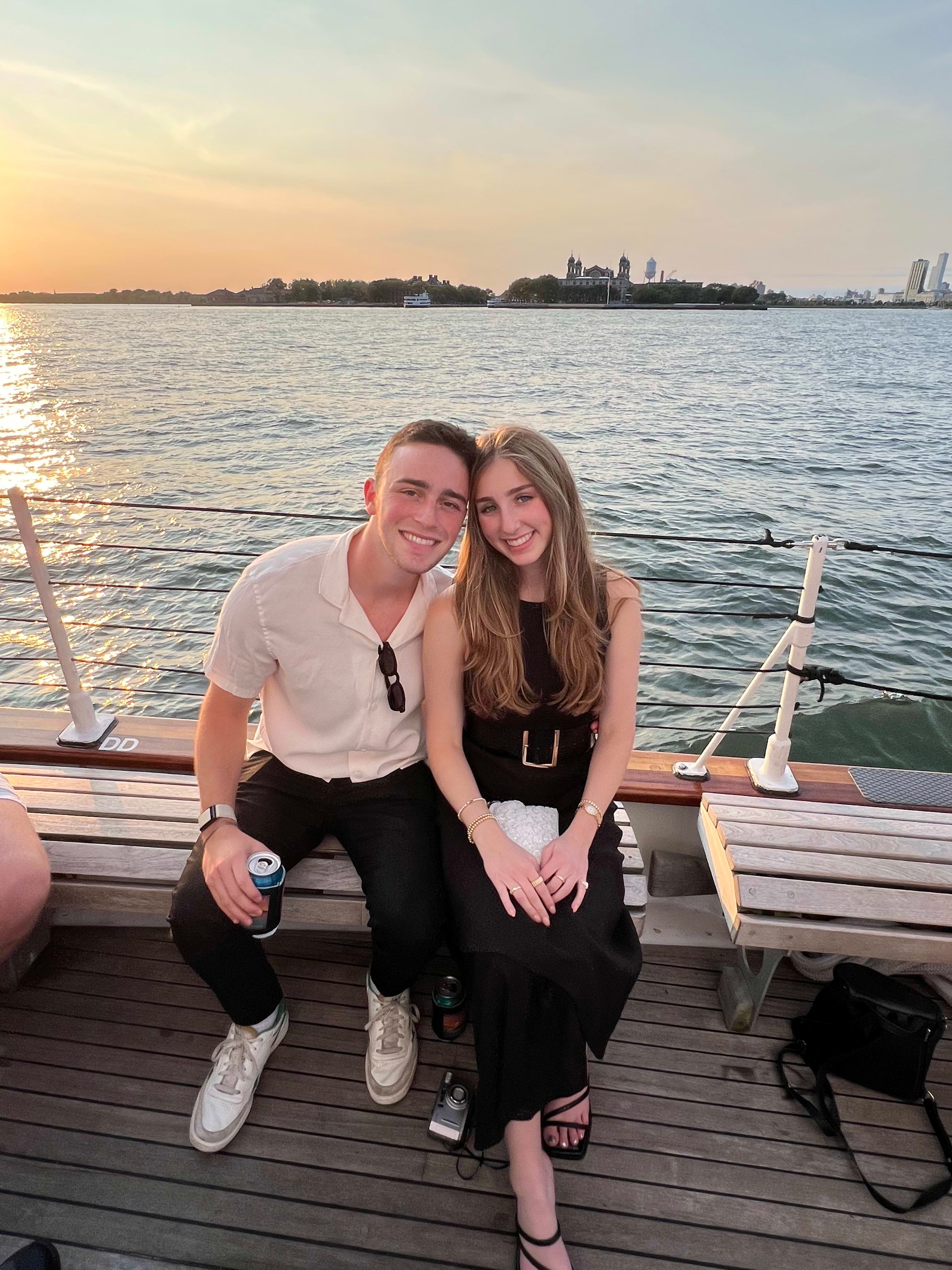 Couple smiling on a boat, sailing at sunset