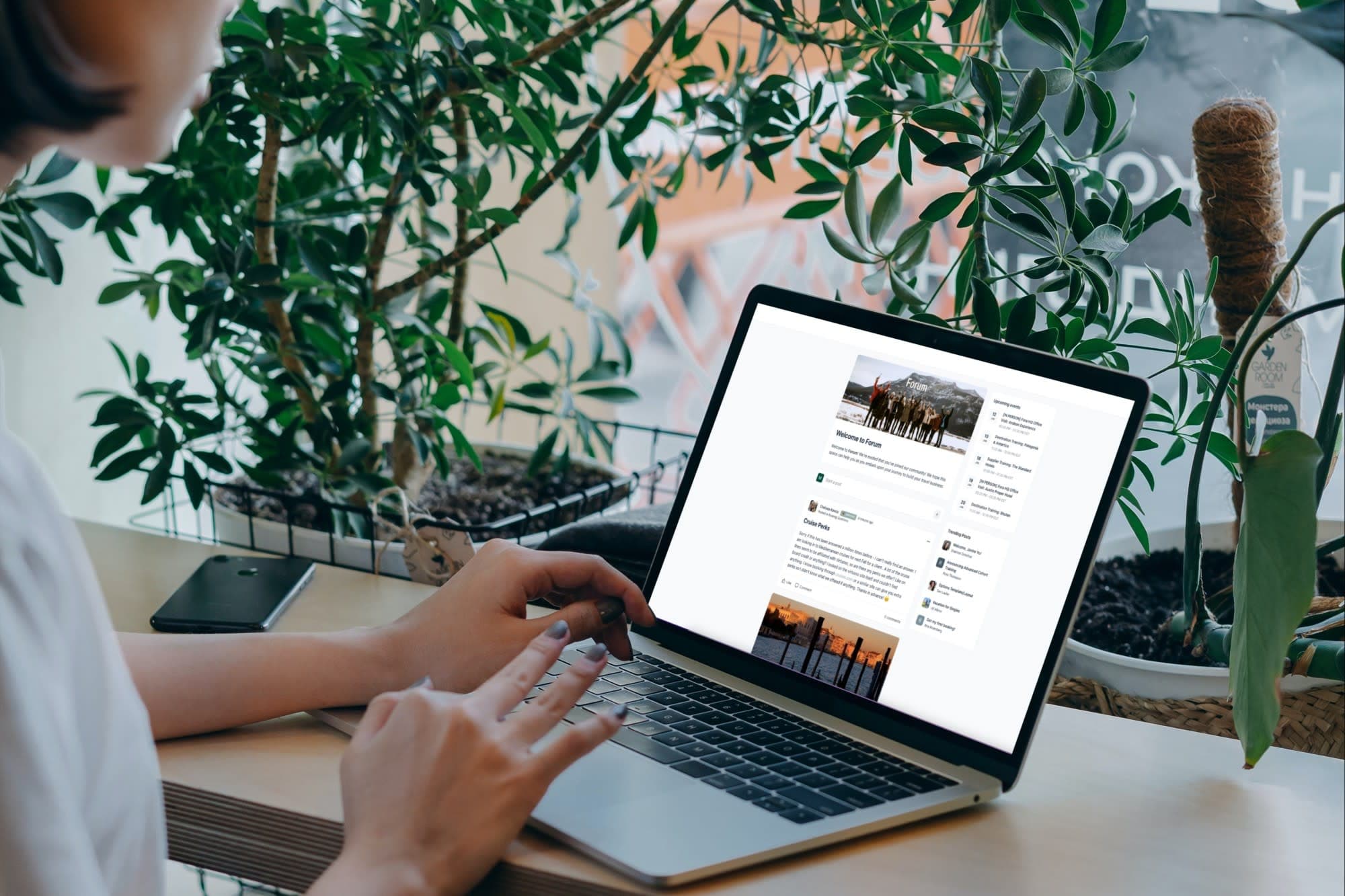 a woman in a gray sweater works on her laptop in a white room