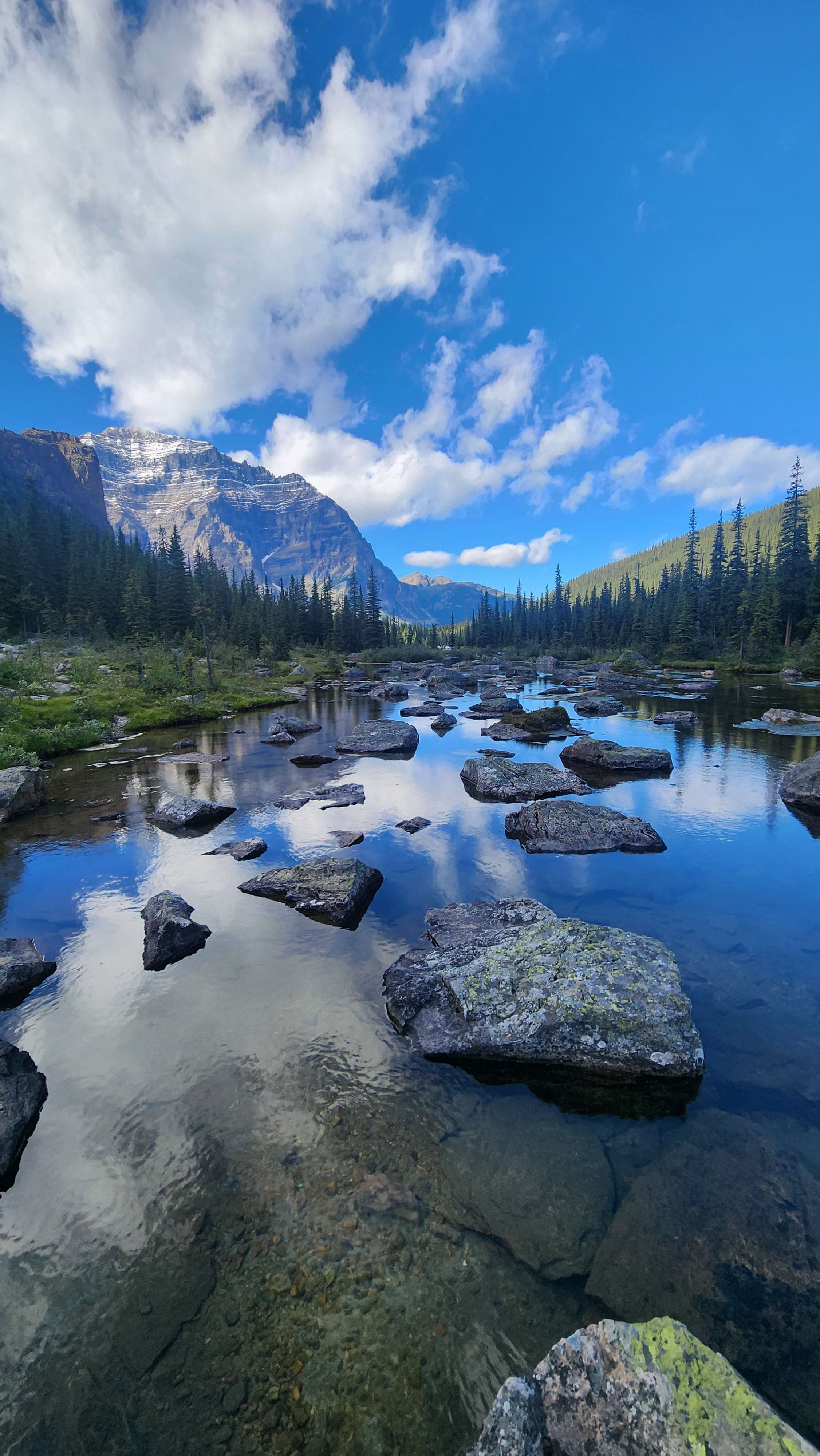 A scenic view of a turquoise-colored lake between mountain ranges during the daytime
