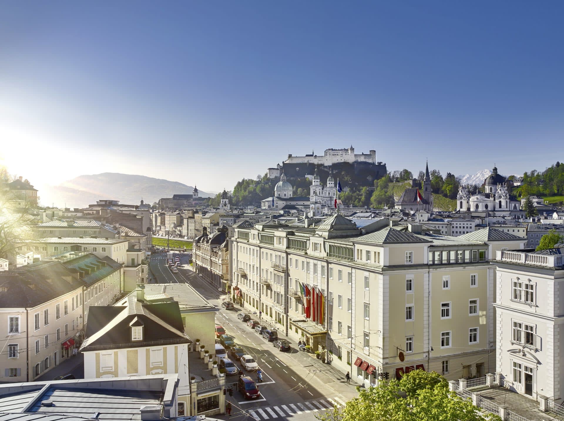 A European city street with a castle on top of a hill in the background