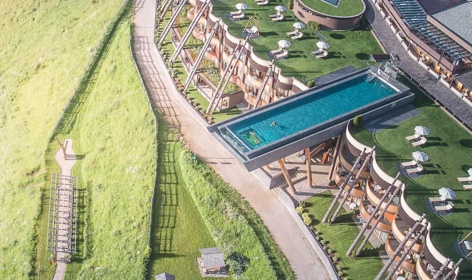 10 Instagram-Worthy Hotel Pools to Visit in 2026 aerial view of pool extending over a green field below