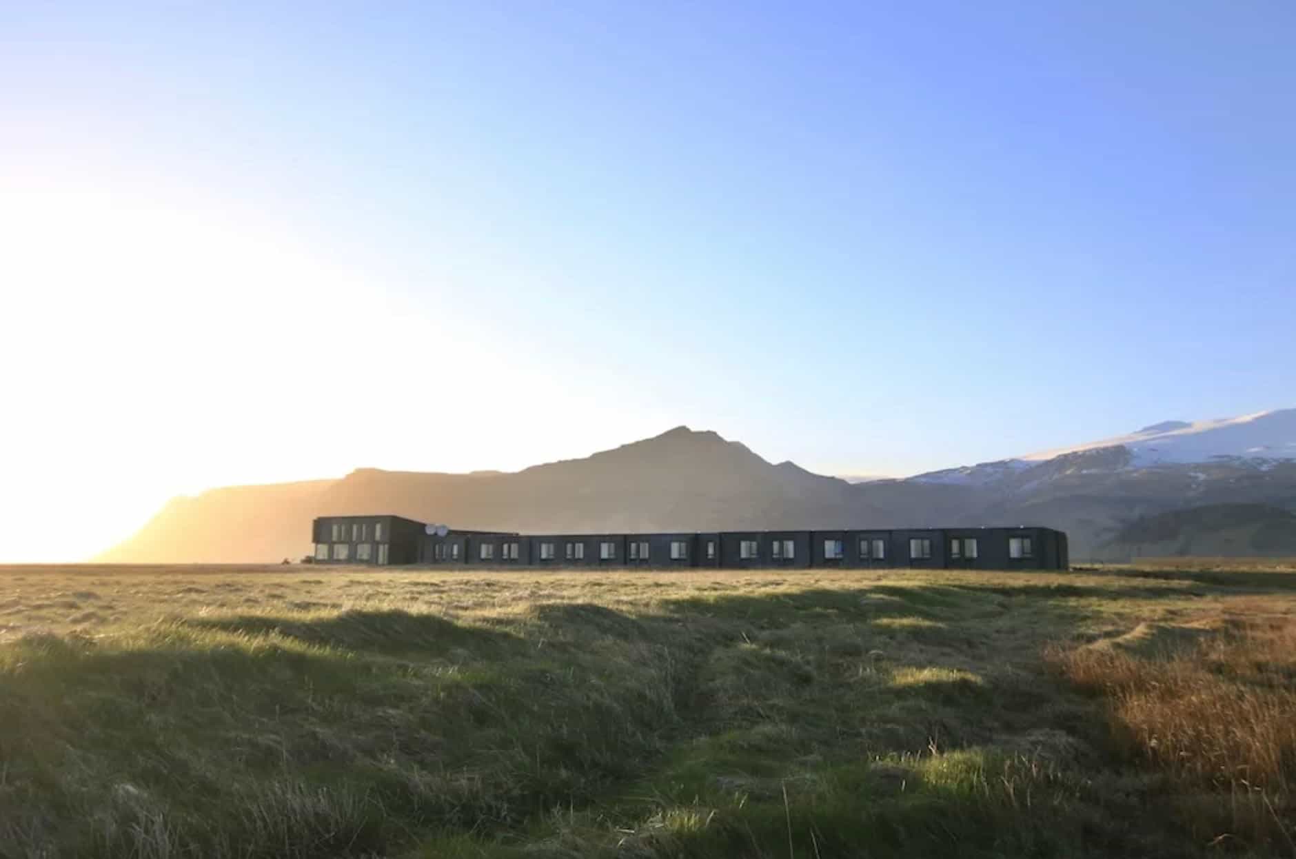 tundra with a low-rise modern hotel with mountains behind it