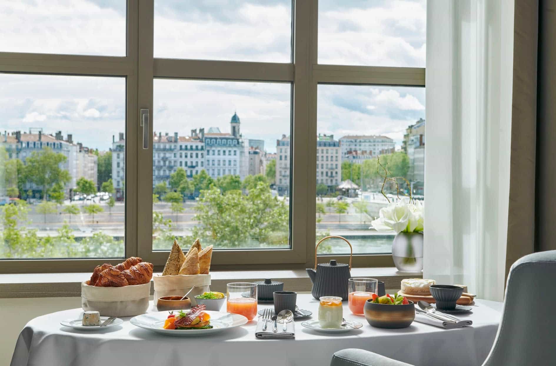 a table set with breakfast overlooking a river and city beyond