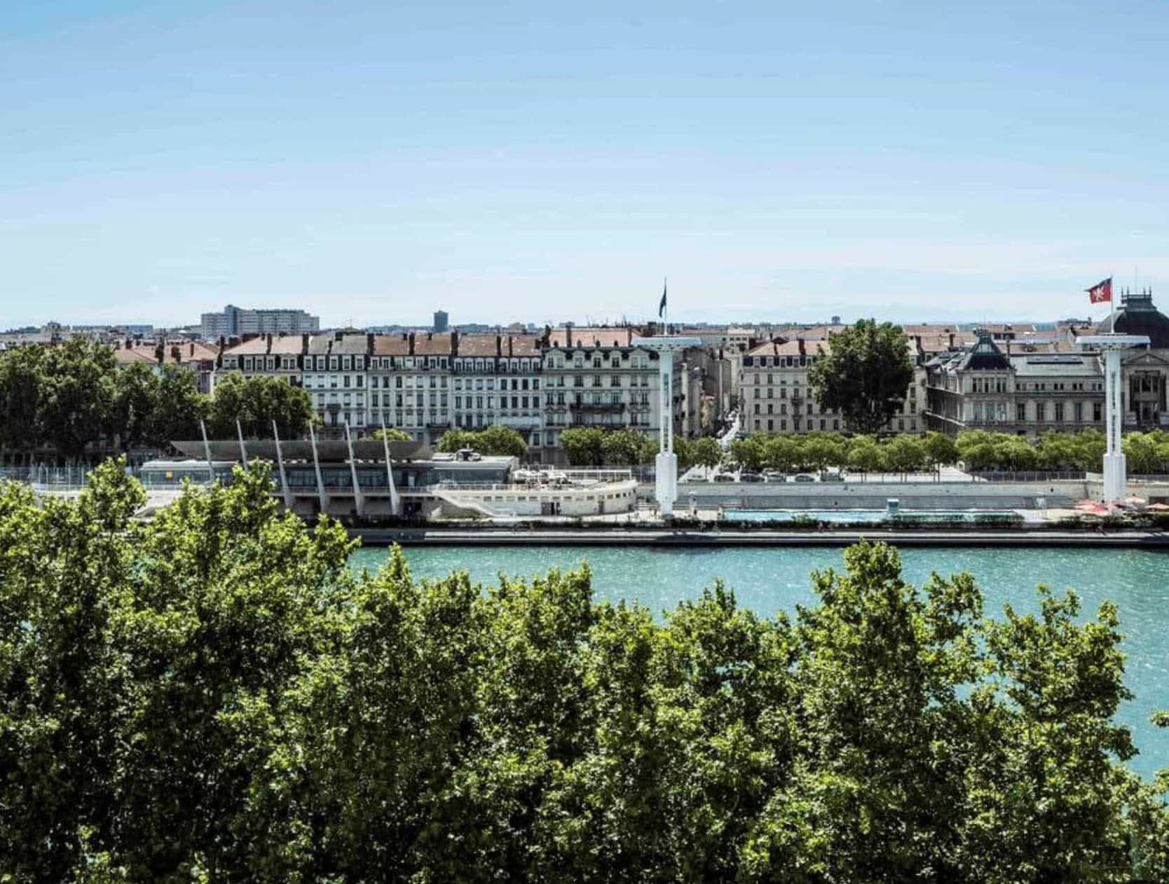 view of a river with city buildings and blue sky beyond