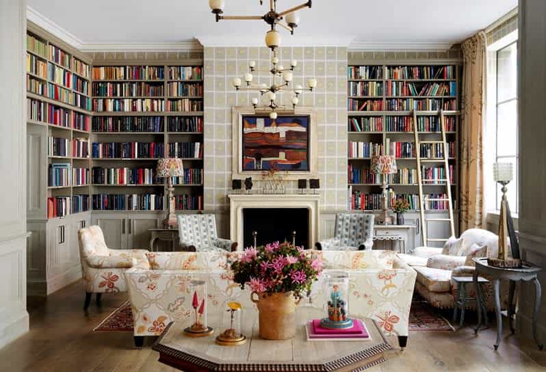 A beautiful hotel library and lounge area with floor-to-ceiling bookshelves, white furnishings, and other bright and colorful decor.