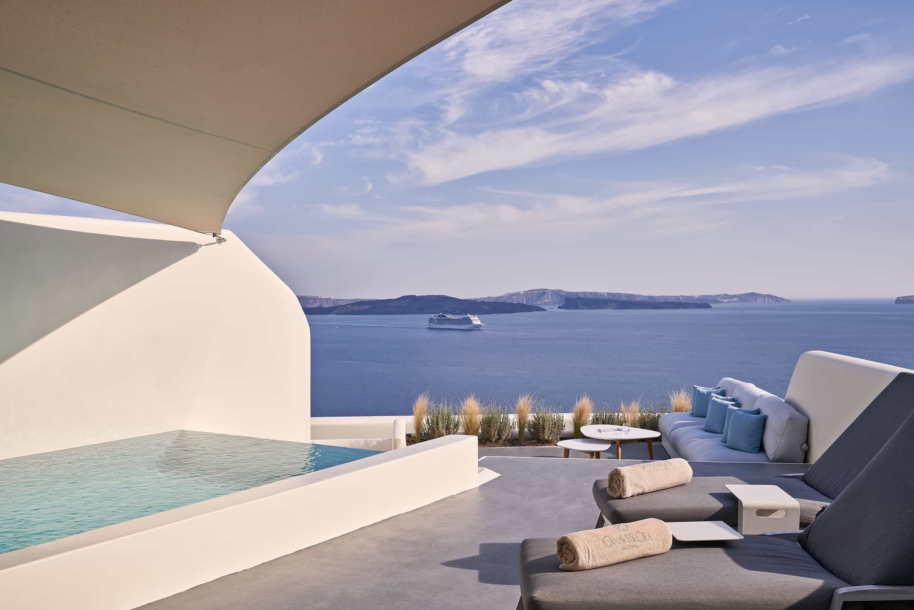 A plunge pool and lounge chairs overlooking the ocean with a cruise ship in the distance during day