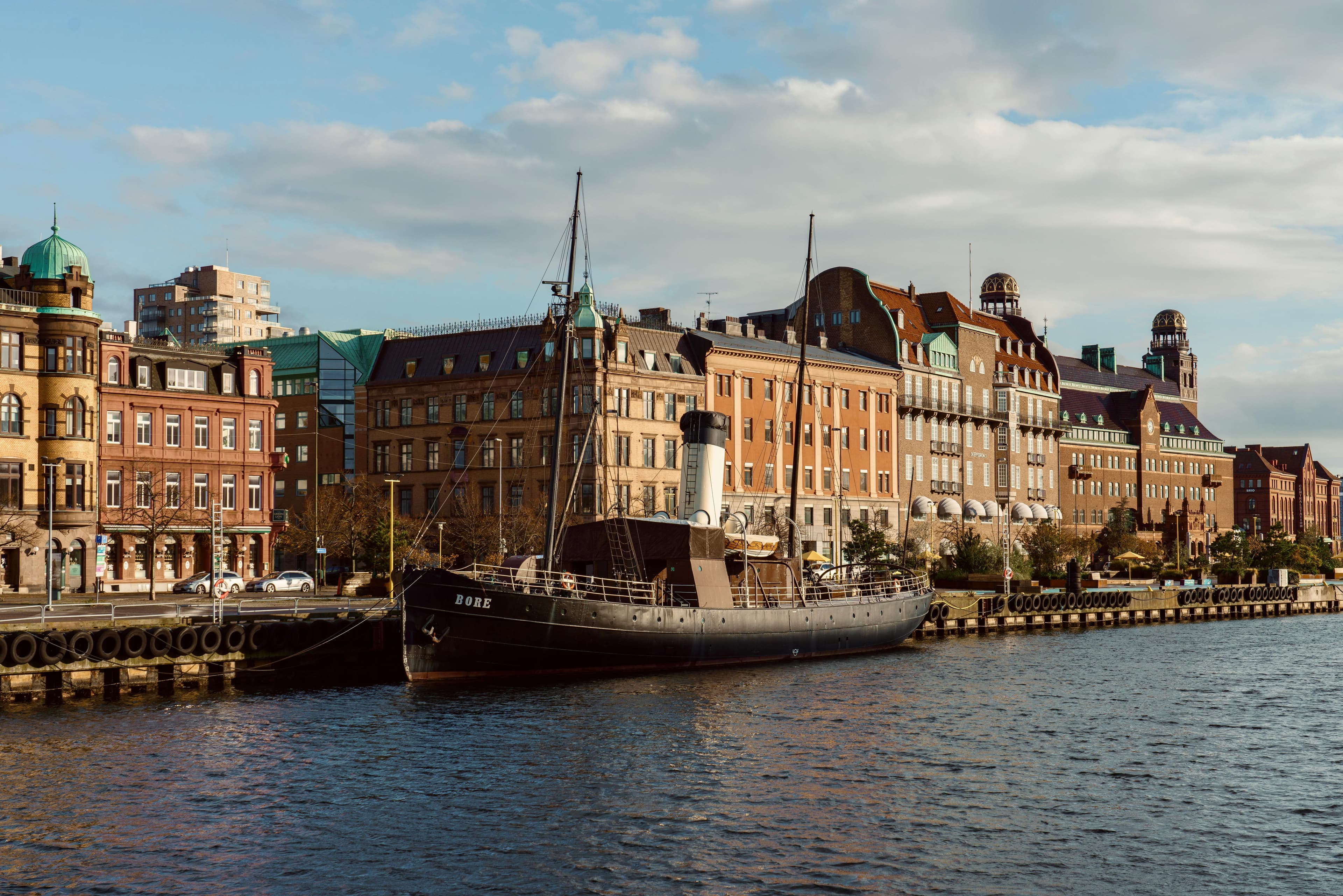 a 19th century icebreaker ship docked on a harborside in the city with brick buildings behind during day