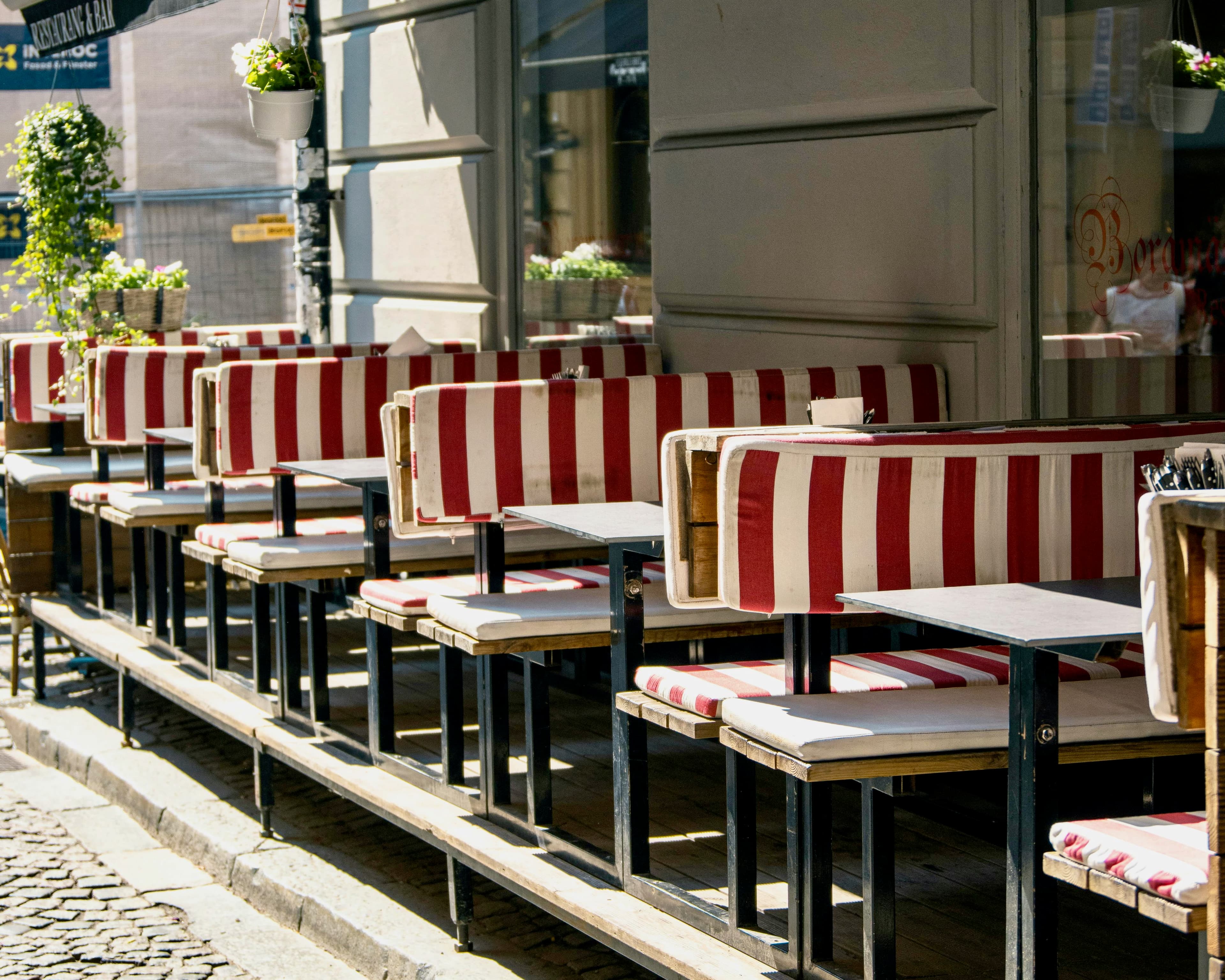 red and white striped outdoor benches with tables lining a restaurant patio during day
