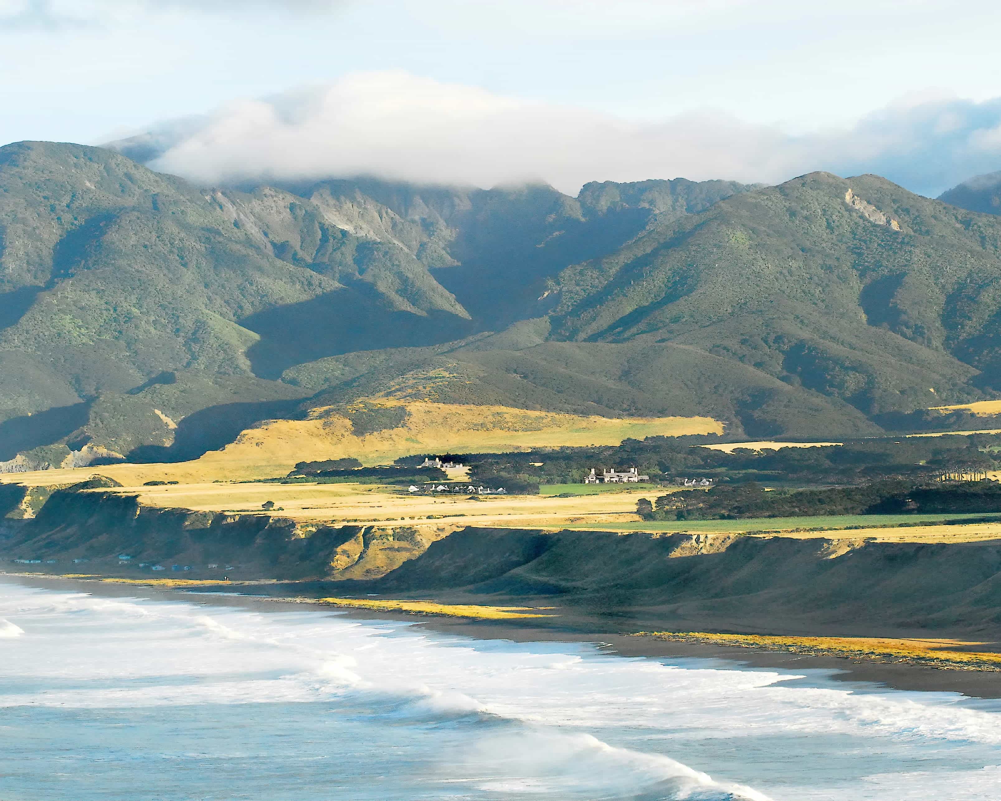 aerial landscape of green cliff coastline with mountains in the background and a country estate