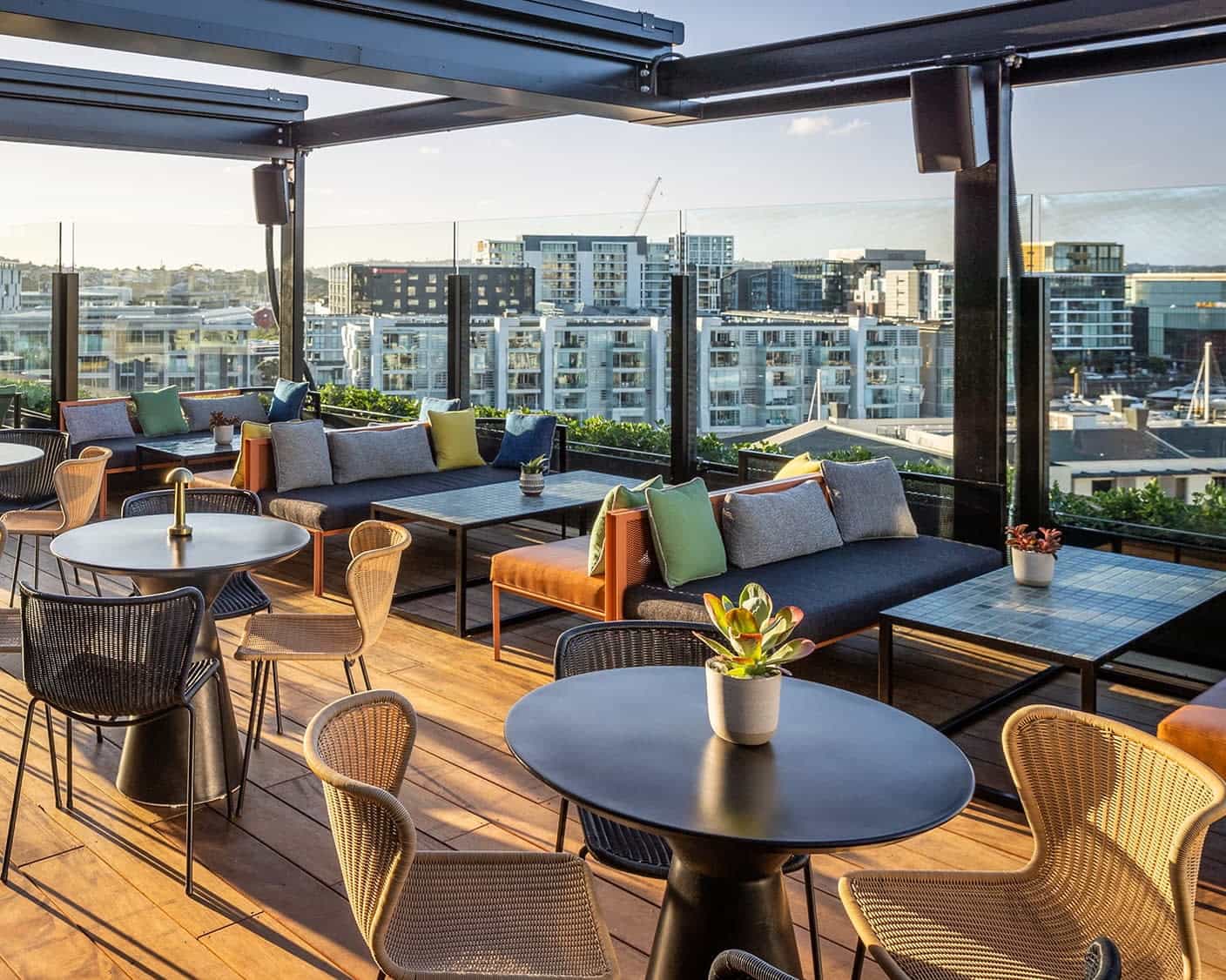 modern rooftop lounge with black cushions and chairs accented by vibrant color pillows and the skyline behind