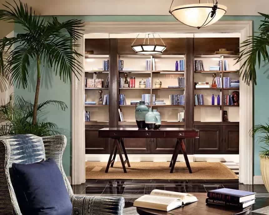 A library setting with chair and books and dark wood shelves and green walls